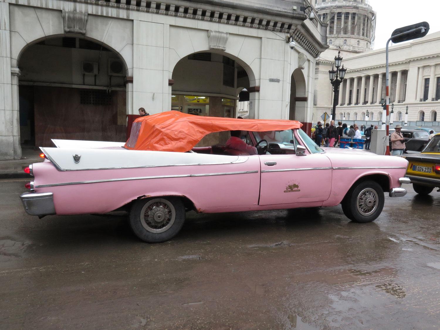 Det regnar inte så ofta i Havanna så sufletterna ser ut som något katten släpat in, även på denna Dodge Convertible från 1955 eller -56. Regeringsbyggnaden Capitolium i bakgrunden.