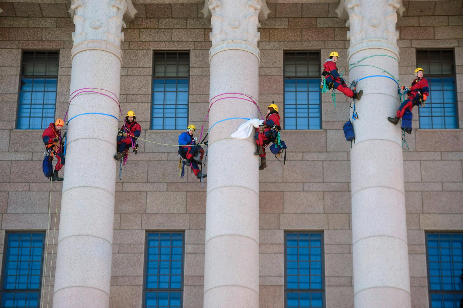 Iklädda Greenpeace-overaller klättrade miljöaktivister upp på de stora pelarna vid det finländska riksdagshuset på onsdagen.