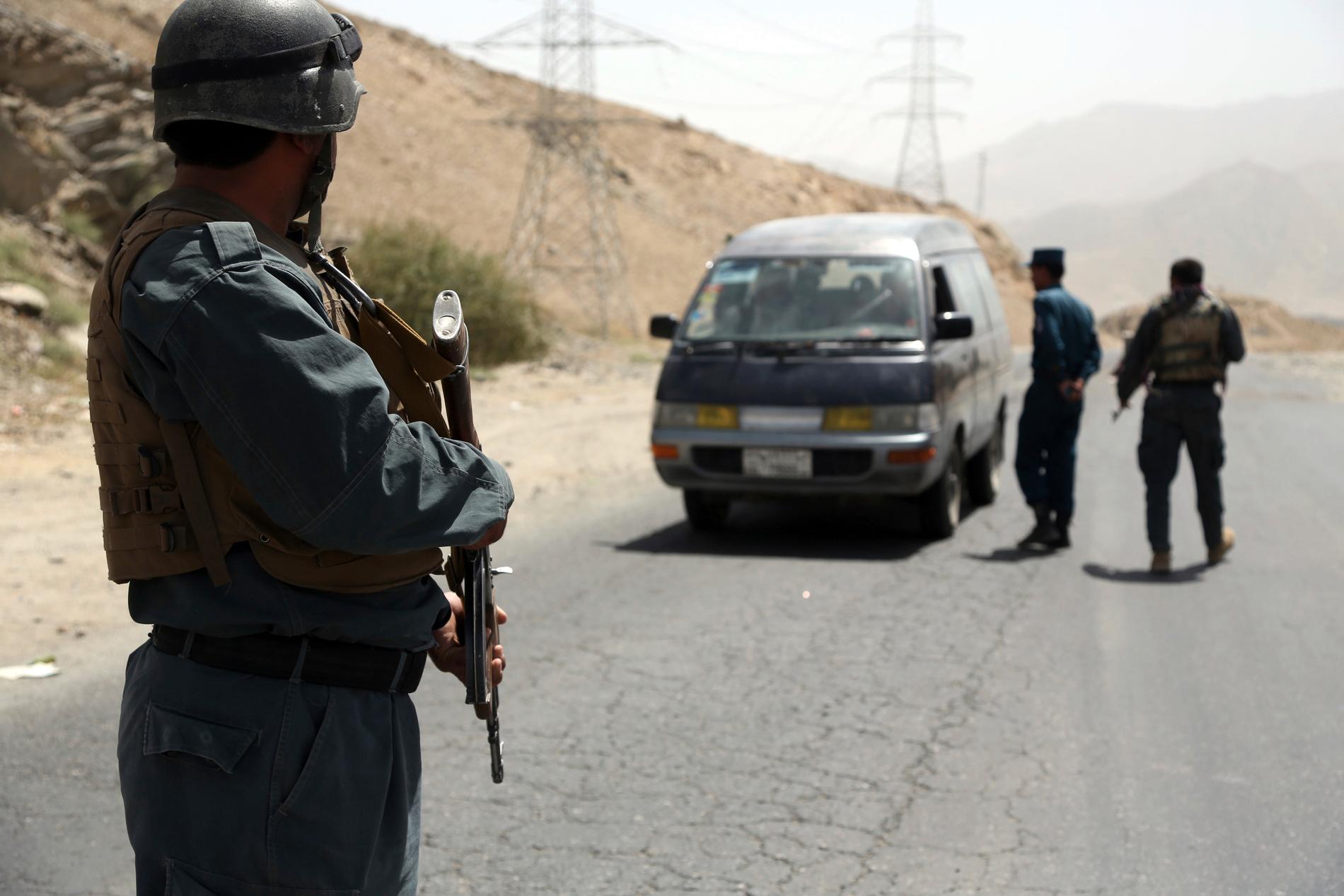 Afghanska poliser söker igenom ett fordon vid en motorväg väster om Kabul. Arkivbild.