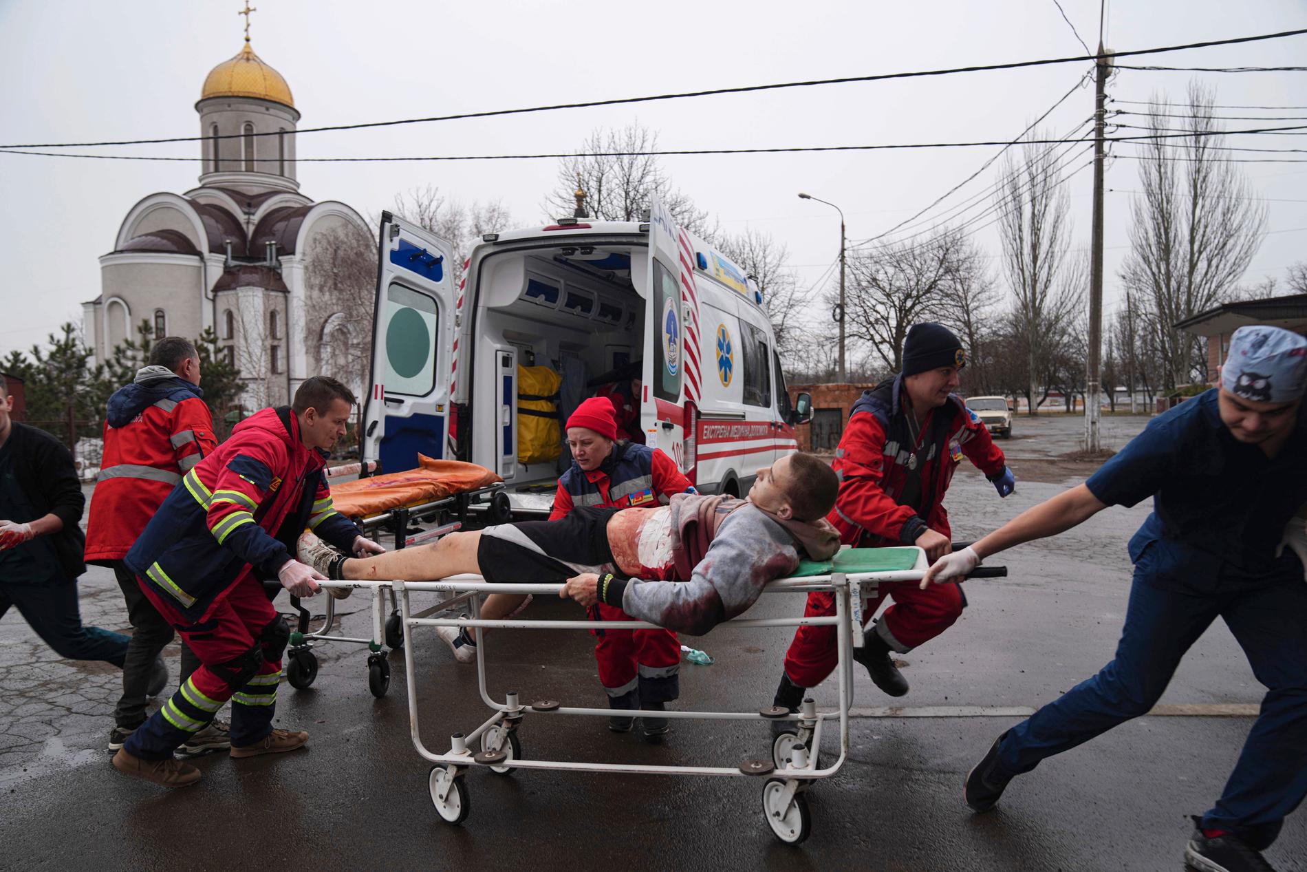 Ambulanspersonal förflyttar en skadad man till en barnmorskemottagning som gjorts om till sjukvårdsmottagning den första mars. I dag uppger Ryssland att eldupphör ska råda i staden så att civila kan lämna via en ”human korridor”. 