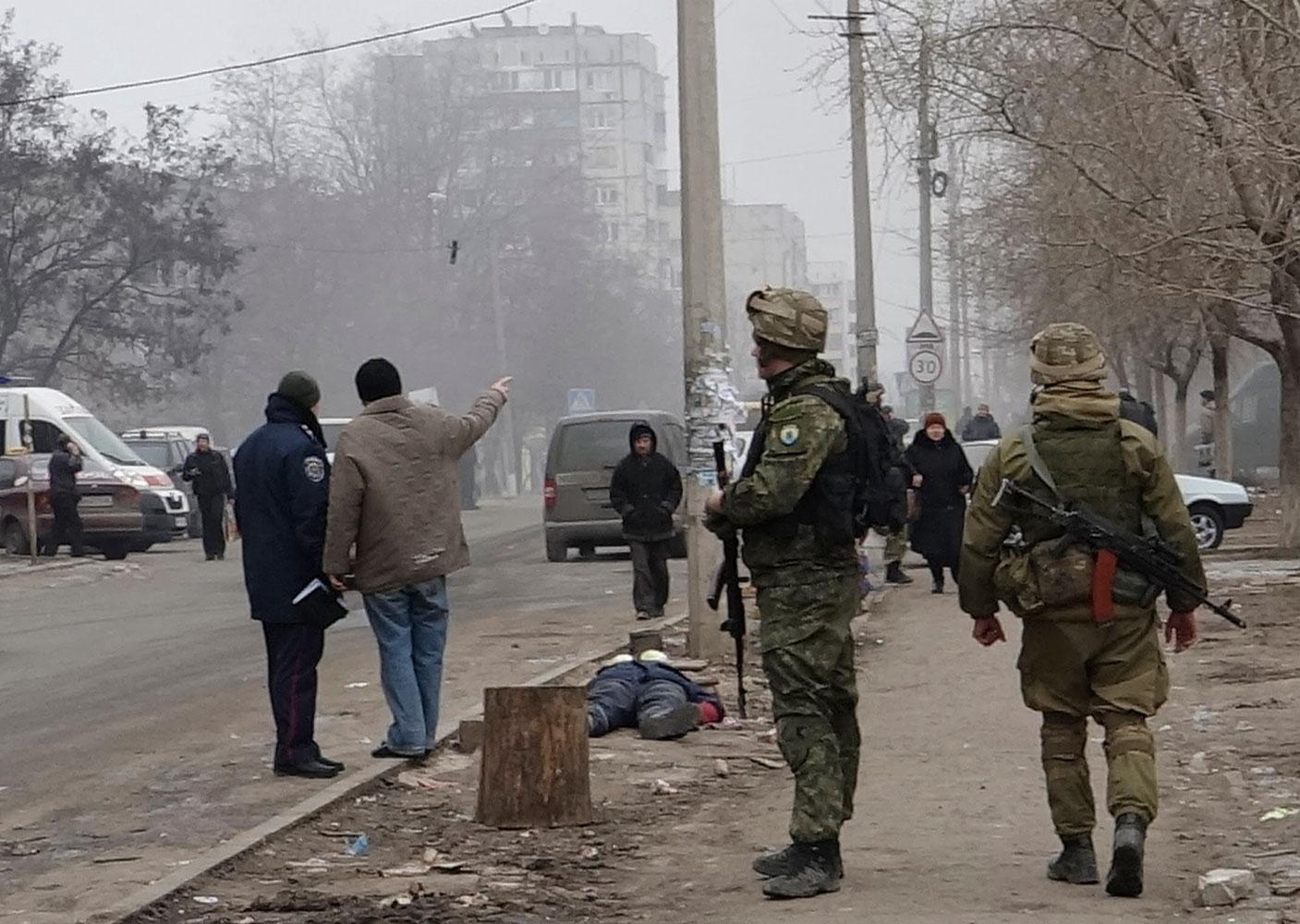 Ukrainska regeringssoldater patrullerar i Mariupol. På gatan ligger en död man.