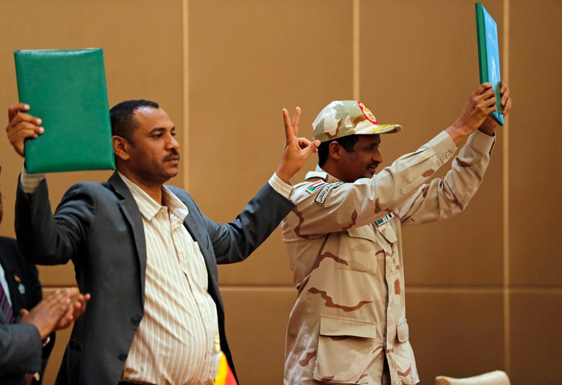 Protestledaren Ahmed Rabie (vänster) och generalen Mohammed Hamdan Dagalo håller upp ett påskrivet avtal om maktdelning i Khartum den 4 augusti förra året.