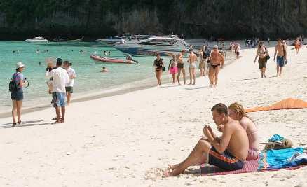Turister njuter av solen och värmen på Phi Phi-öarna i Thailand.