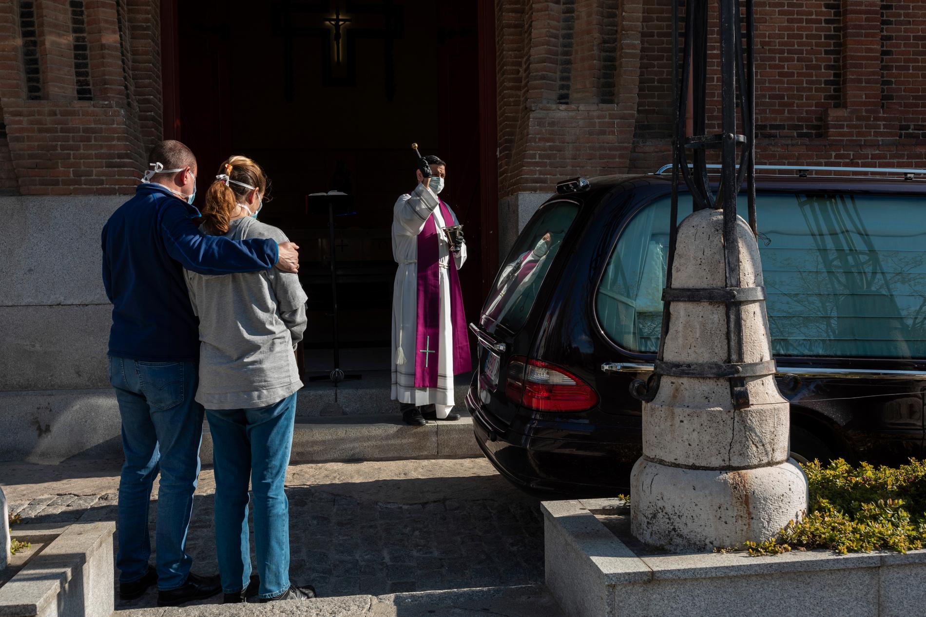 En präst genomför en begravningsceremoni på en av Madrids kyrkogårdar.