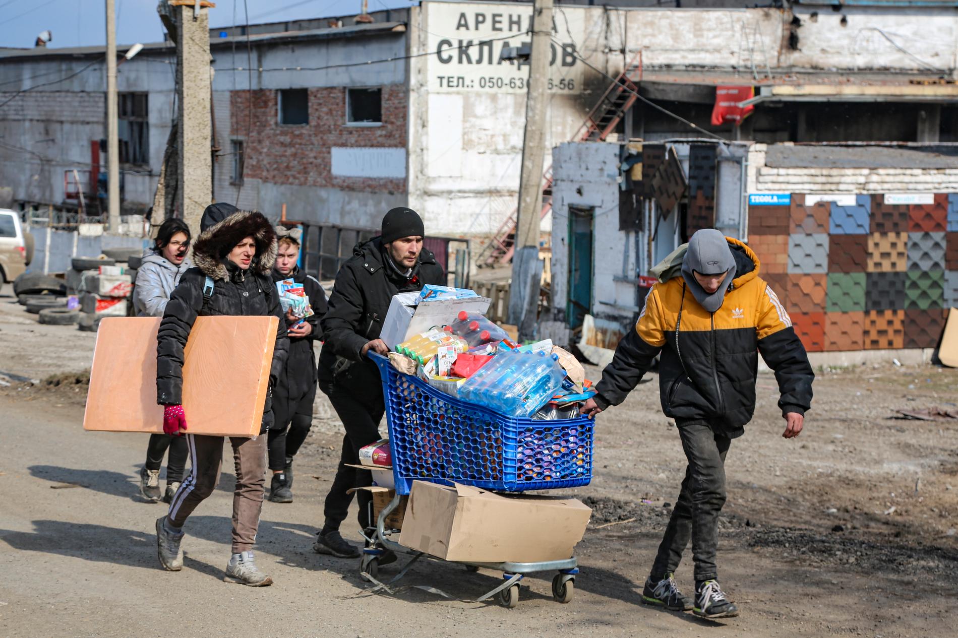 Desperata invånare fraktar vatten från ett matlager i det territorium i utkanten av Mariupol som kontrolleras av de styrande i den självutropade Donetsk-republiken.