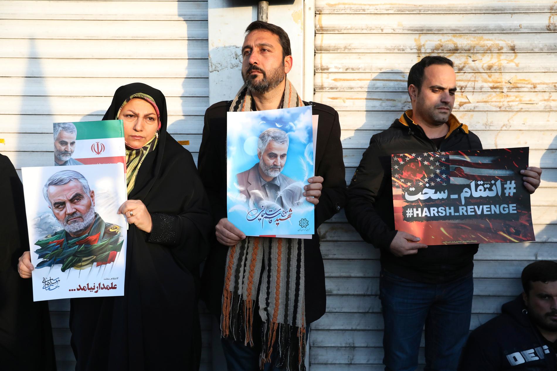 Sörjande håller upp bilder på Qassem Soleimani under begravningsceremonin på måndagen.