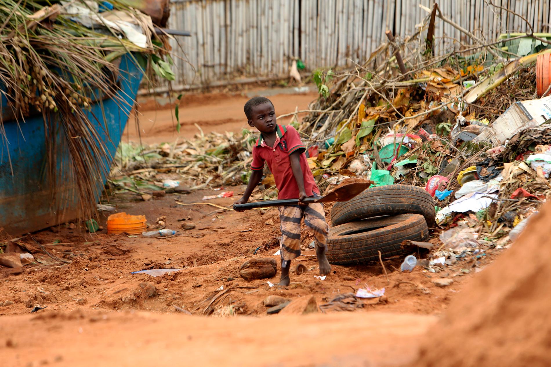 En pojke rensar upp på en väg i den svårt drabbade kuststaden Pemba med hjälp av en spade.