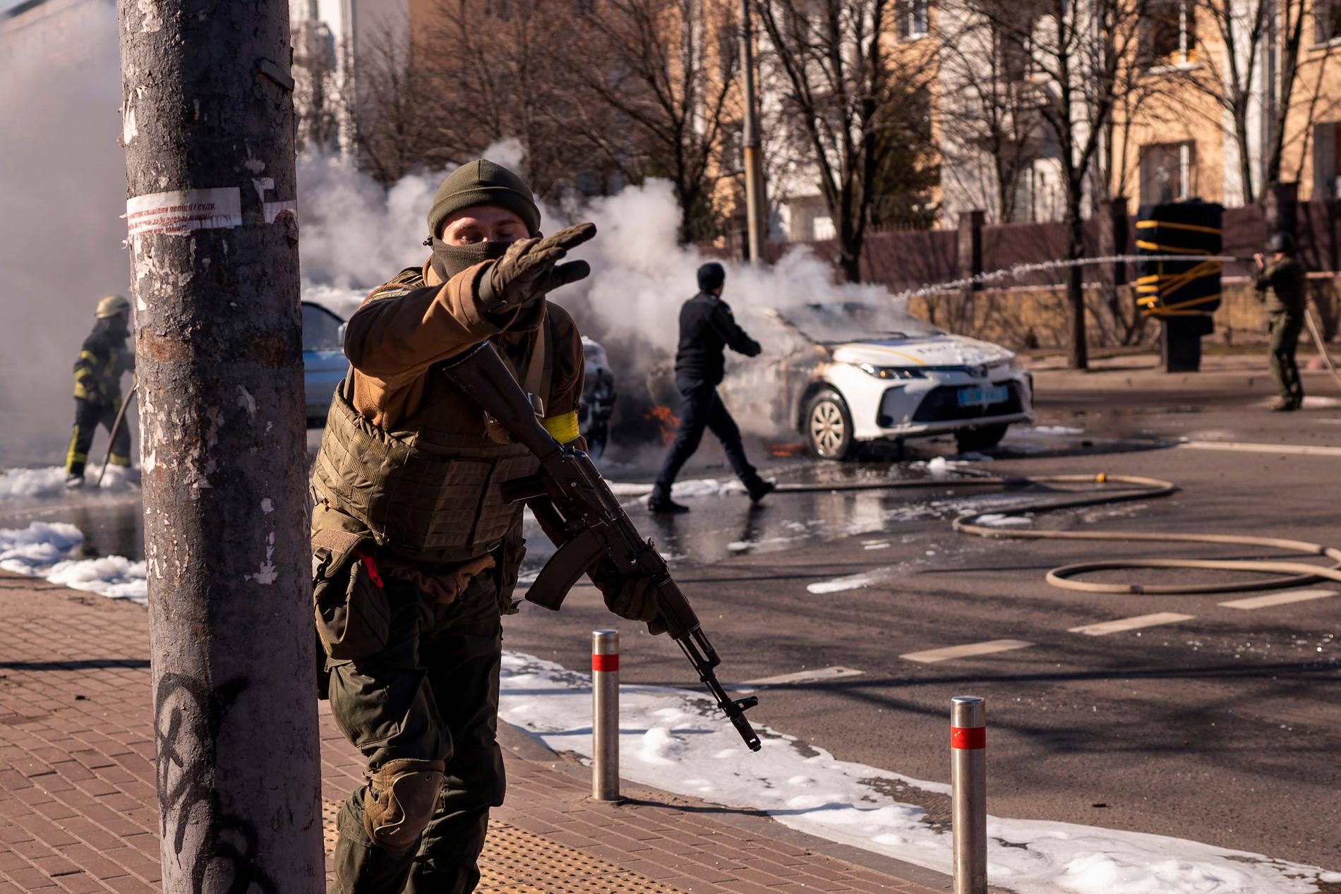 Ukrainska soldater syns vid ett par brinnande bilar i Kiev på lördagen.