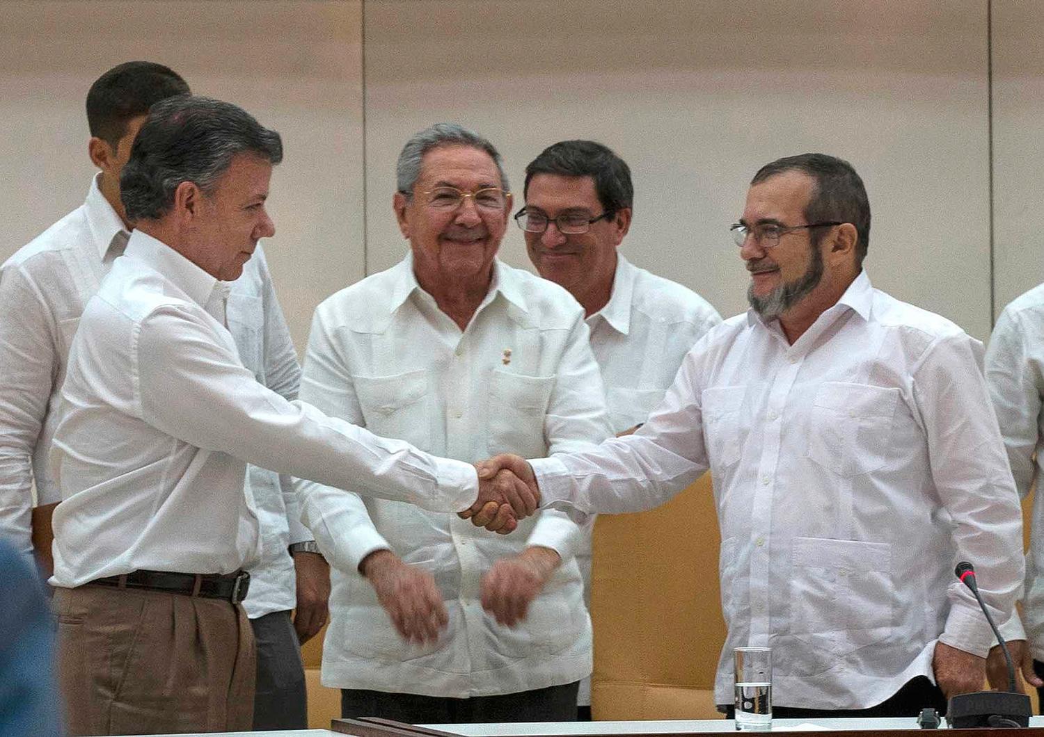Juan Manuel Santos skakar hand med ledaren för Farc, Rodrigo Londono. Bakom står Kubas president  Raúl Castro, som hjälpte till att medla i fredsförhandlingarna.