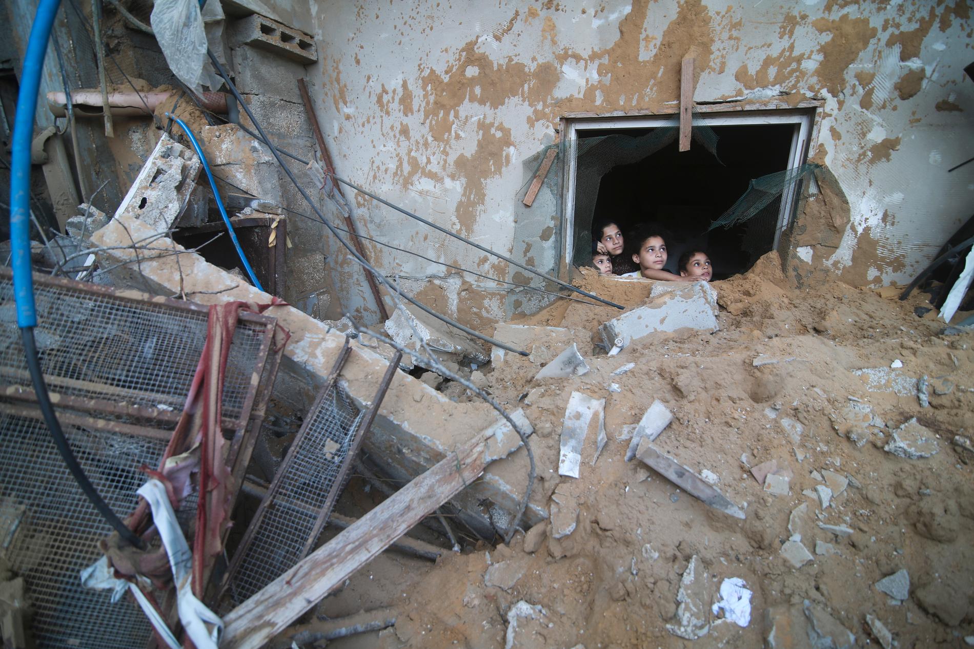 Barn tittar ut genom ett fönster i ett sönderbombat hus i Rafah.
