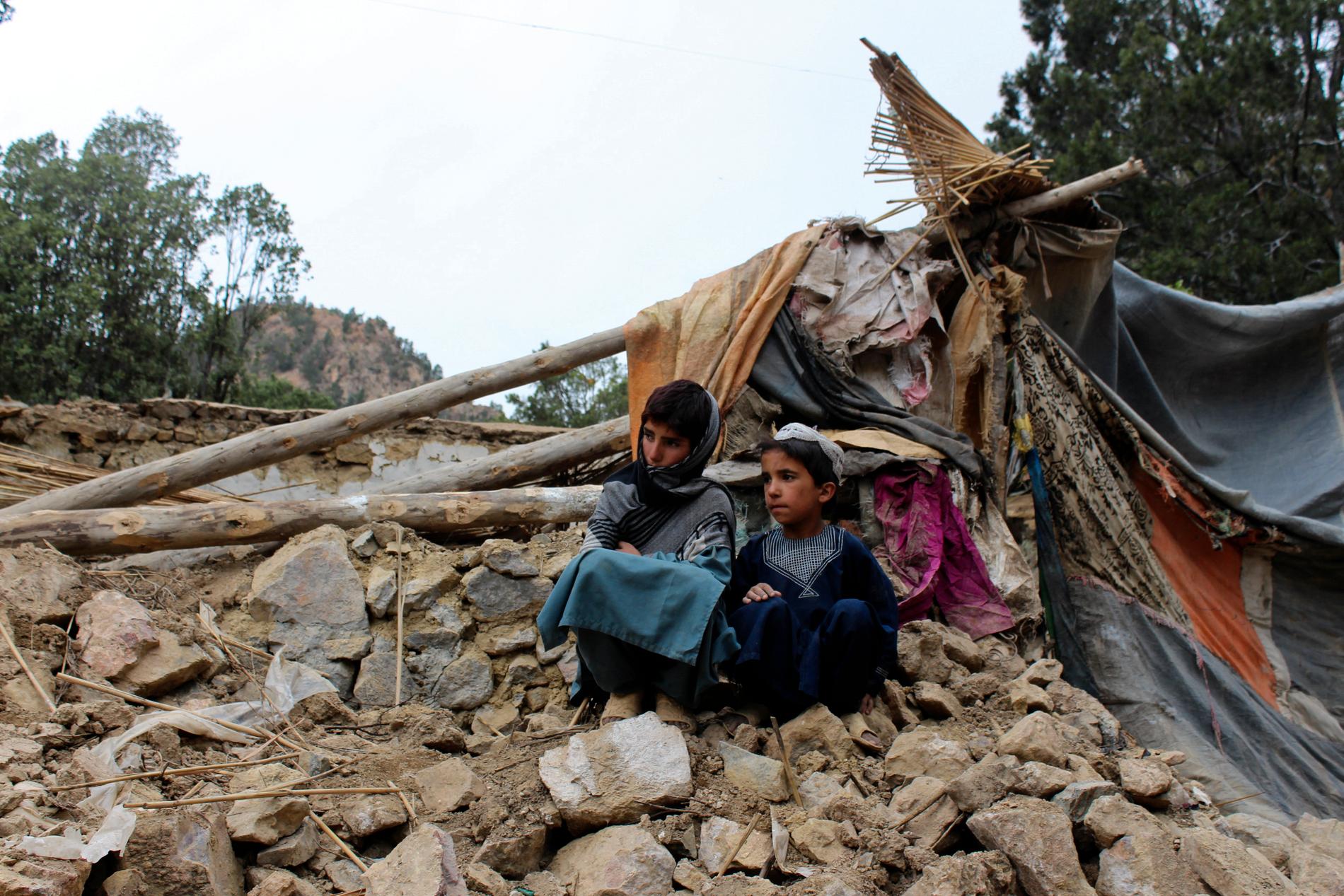Afghanska pojkar vid ett av de många hus som förstördes i skalvet.