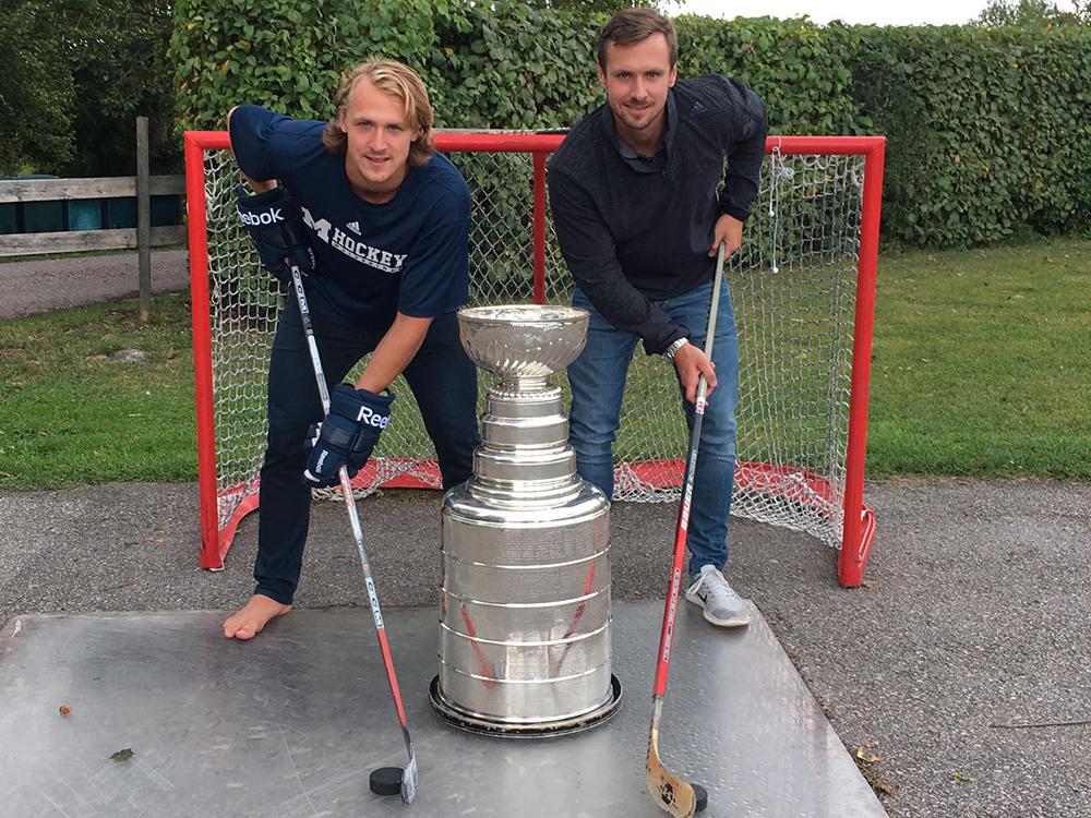 DÄR ALLT BÖRJADE Bröderna Carl och Bobbie Hagelin med Stanley Cup-bucklan vid landhockeyplanen på mammas gata.