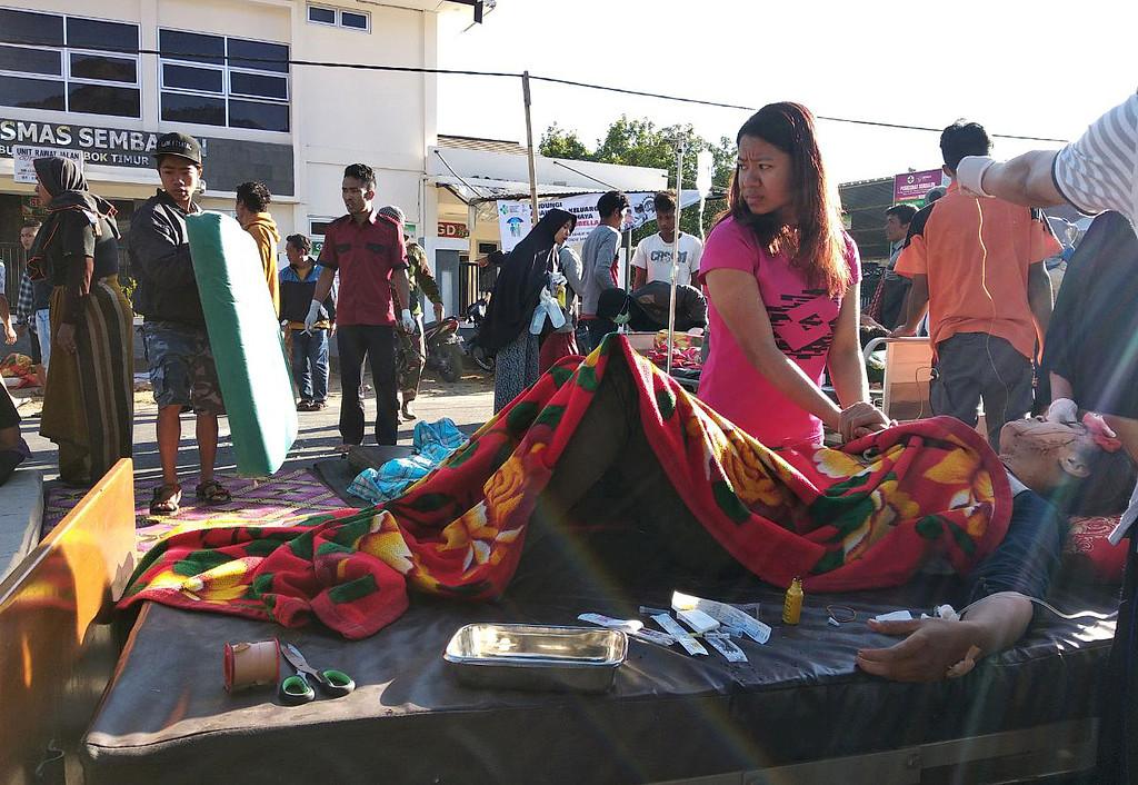 En kvinna står intill en skadad person utanför ett sjukhus på Lombok.
