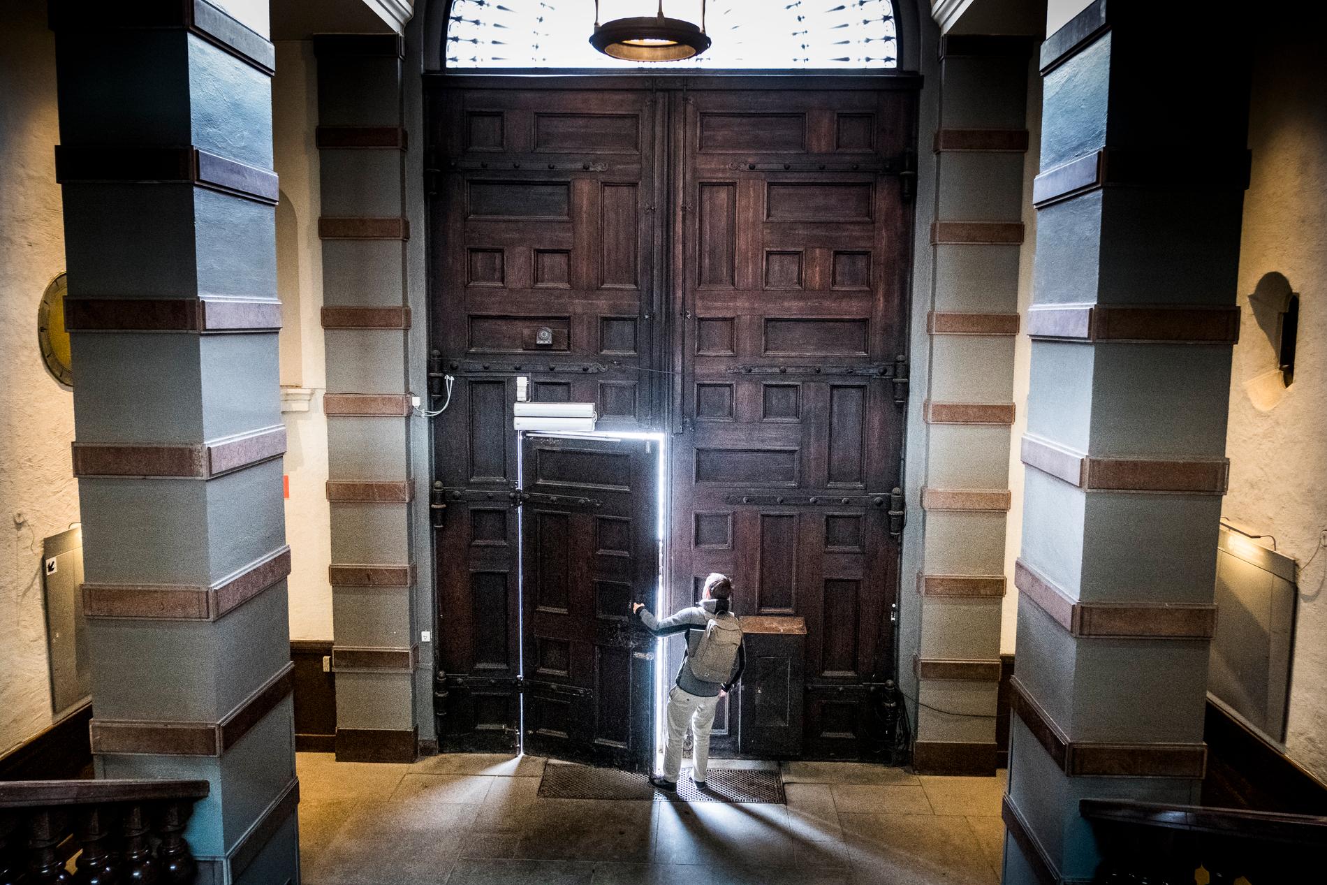 En elev öppnar ytterdörren till Handelshögskolan i Stockholm.