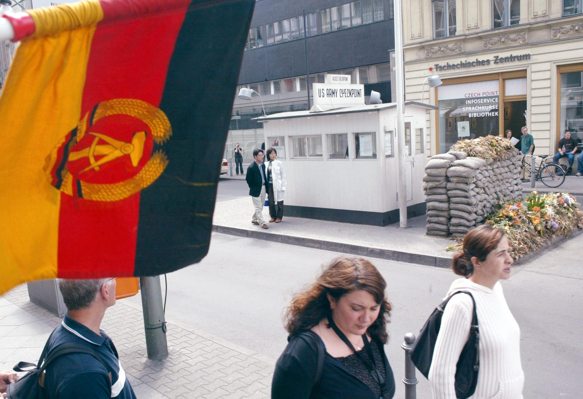 En östtysk flagga vajar vid den tidigare gränsövergången Checkpoint Charlie i Berlin, numera ett turistmål.