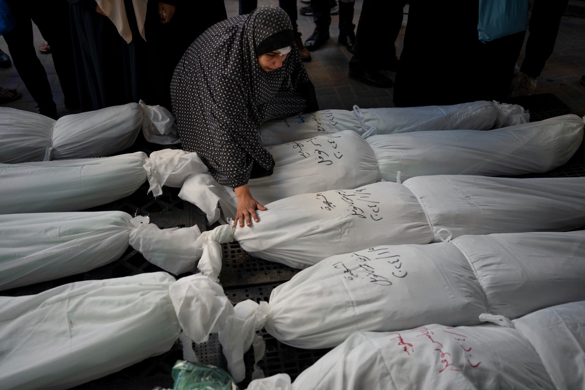 Människor sörjer sina nära som dött i en israelisk attack mot Gazaremsan i januari 2024. De döda kropparna inlindade i vita lakan ligger utanför ett bårhus i Rafah.