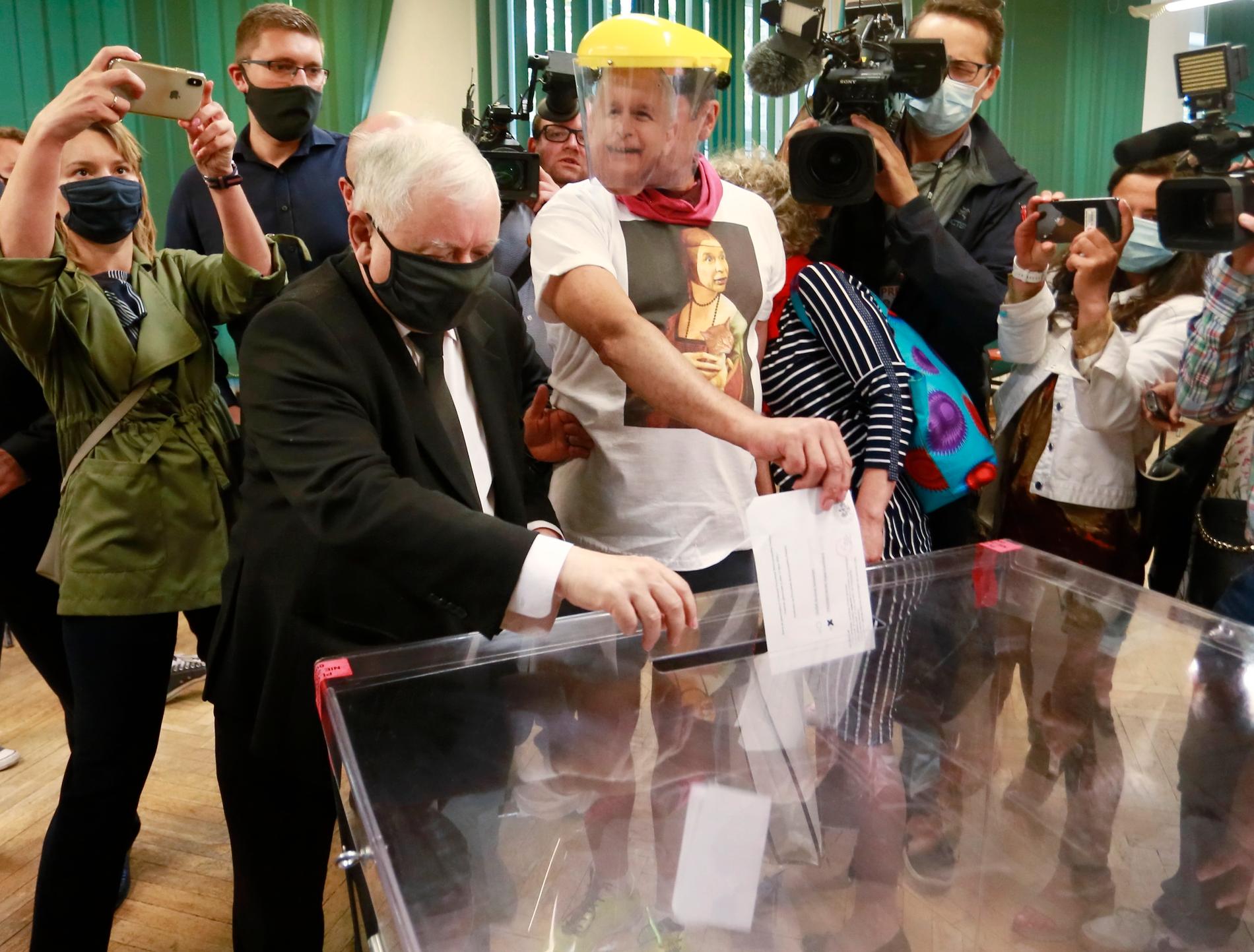 Jaroslaw Kaczynski (till vänster) röstade i en vallokal i huvudstaden Warszawa. Till höger en väljare som bär en mask som föreställer Kaczynski.