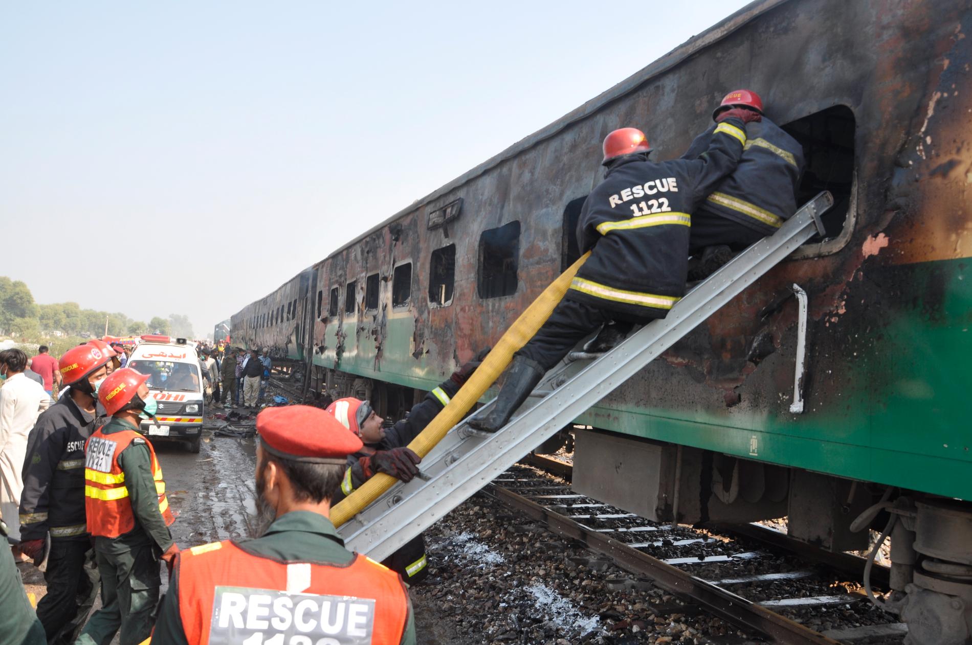 Räddningsarbetare letar efter passagerare i det utbrunna tåget.