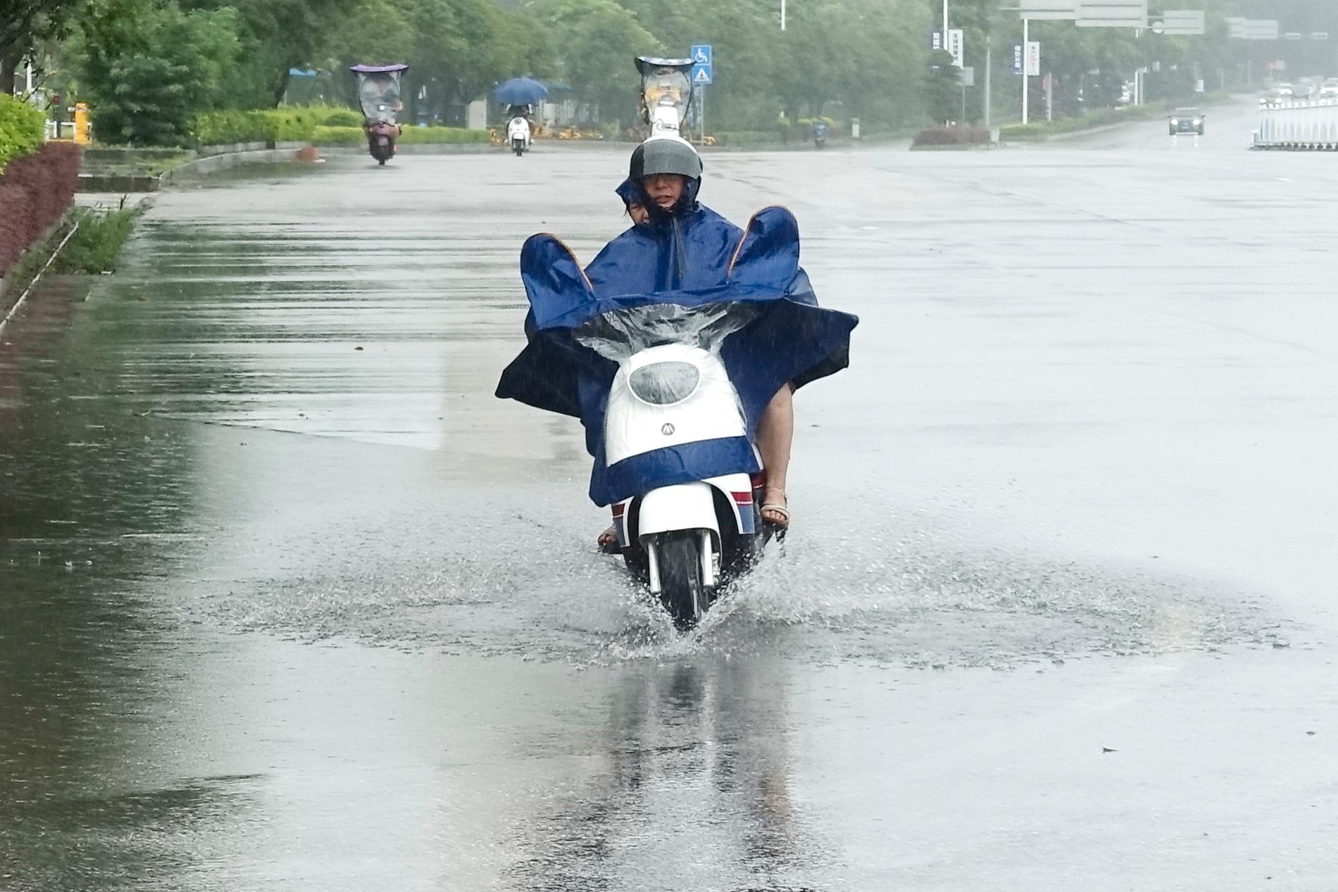 I Kina har nederbörden slagit rekord i en del provinser i juni. Här åker en man omkring på en moped i Hezhou.