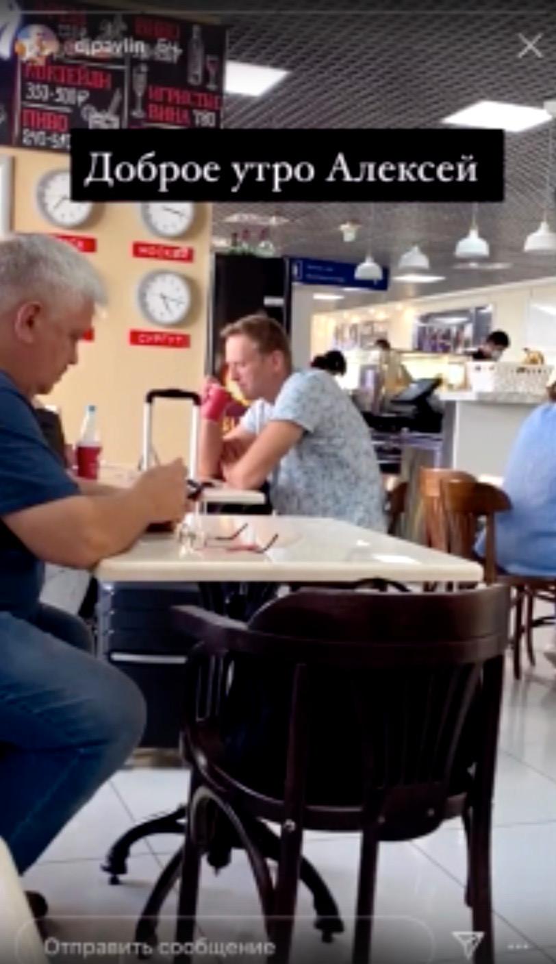 Bild tagen ur medpassageraren Pavel Lebedevs film, där Aleksej Navalnyj dricker te på flygplatsen i Tomsk. ”God morgon, Aleksej”, står det skrivet i bilden.