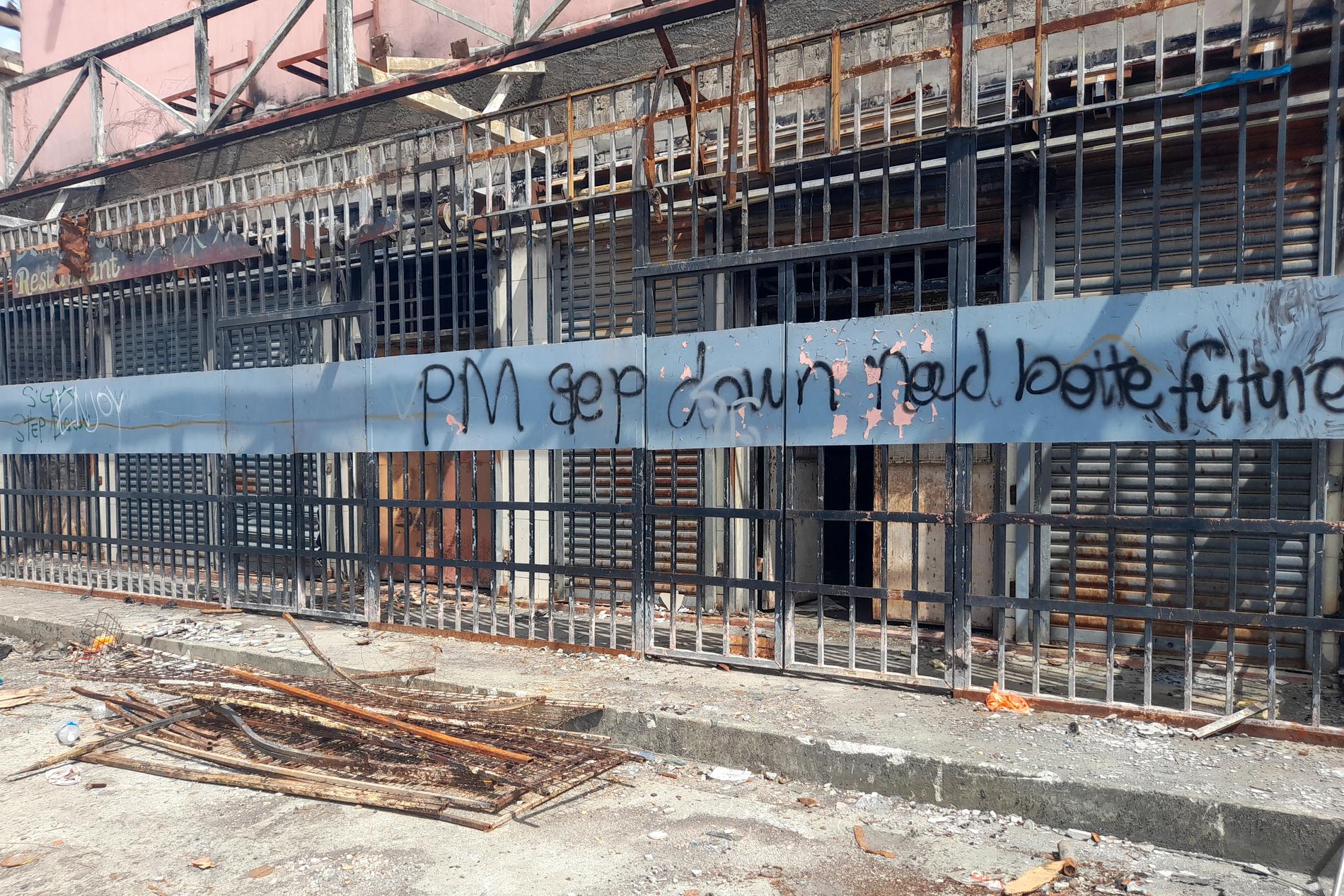 Klotter på brandhärjade byggnader i Chinatown i Honiara, Salomonöarna, efter upproren i november 2021.