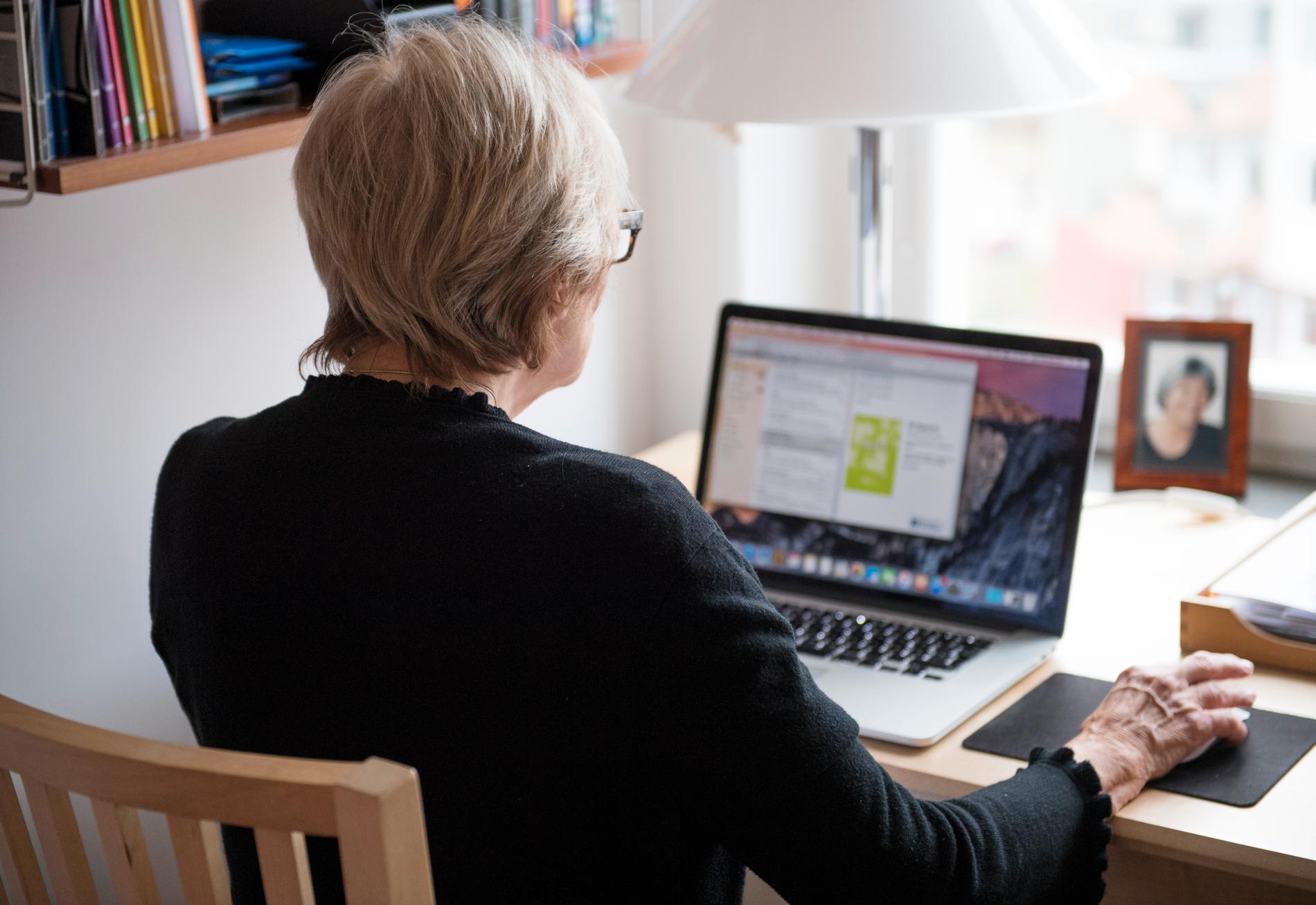 En äldre kvinna framför en dator.