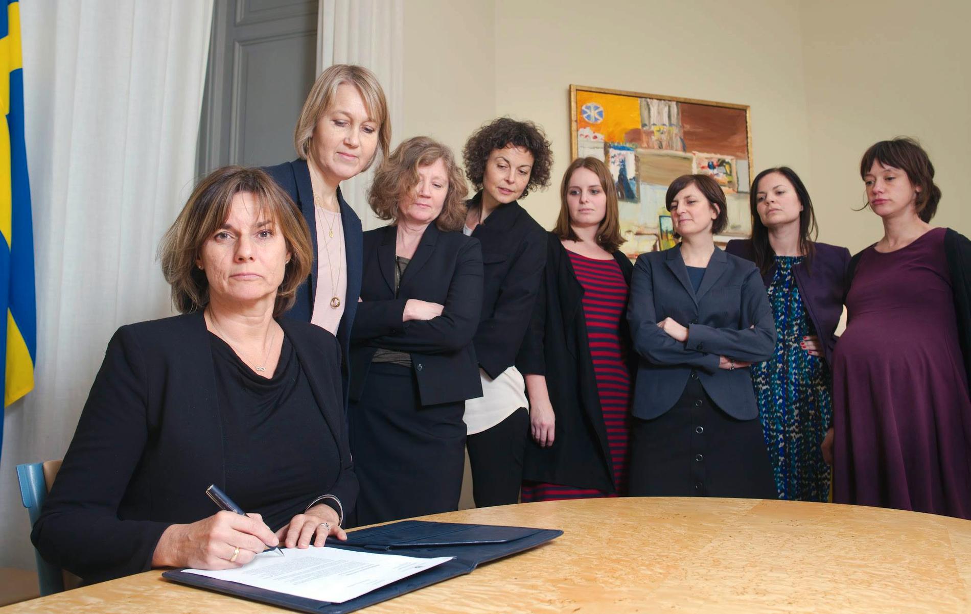 Isabella Lövin (MP) skriver på ny klimatlag omgiven av sju kvinnor.
