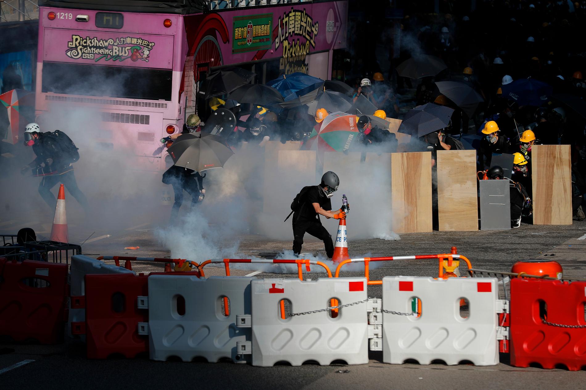 Demonstranter möts av tårgas i Hongkong under måndagens generalstrejk.