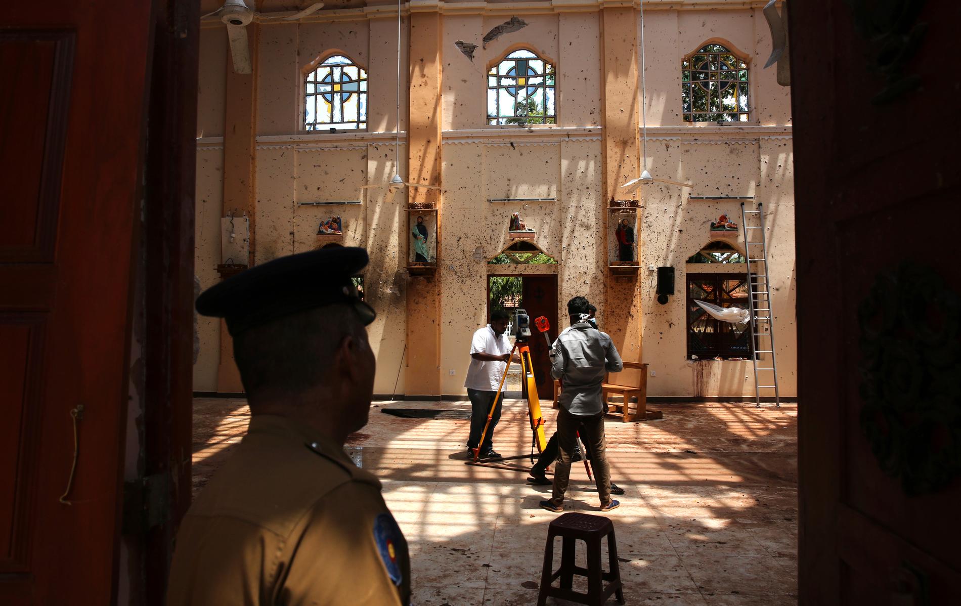 En polis står vakt när överlevare arbetar i kyrkan S:t Sebastian norr om Colombo.