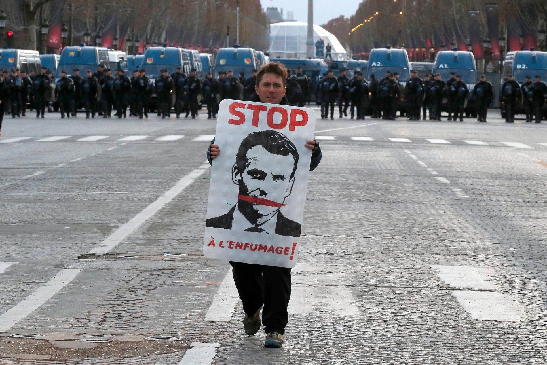 En demonstrant med ett porträtt på president Macron på Champs-Élysées.