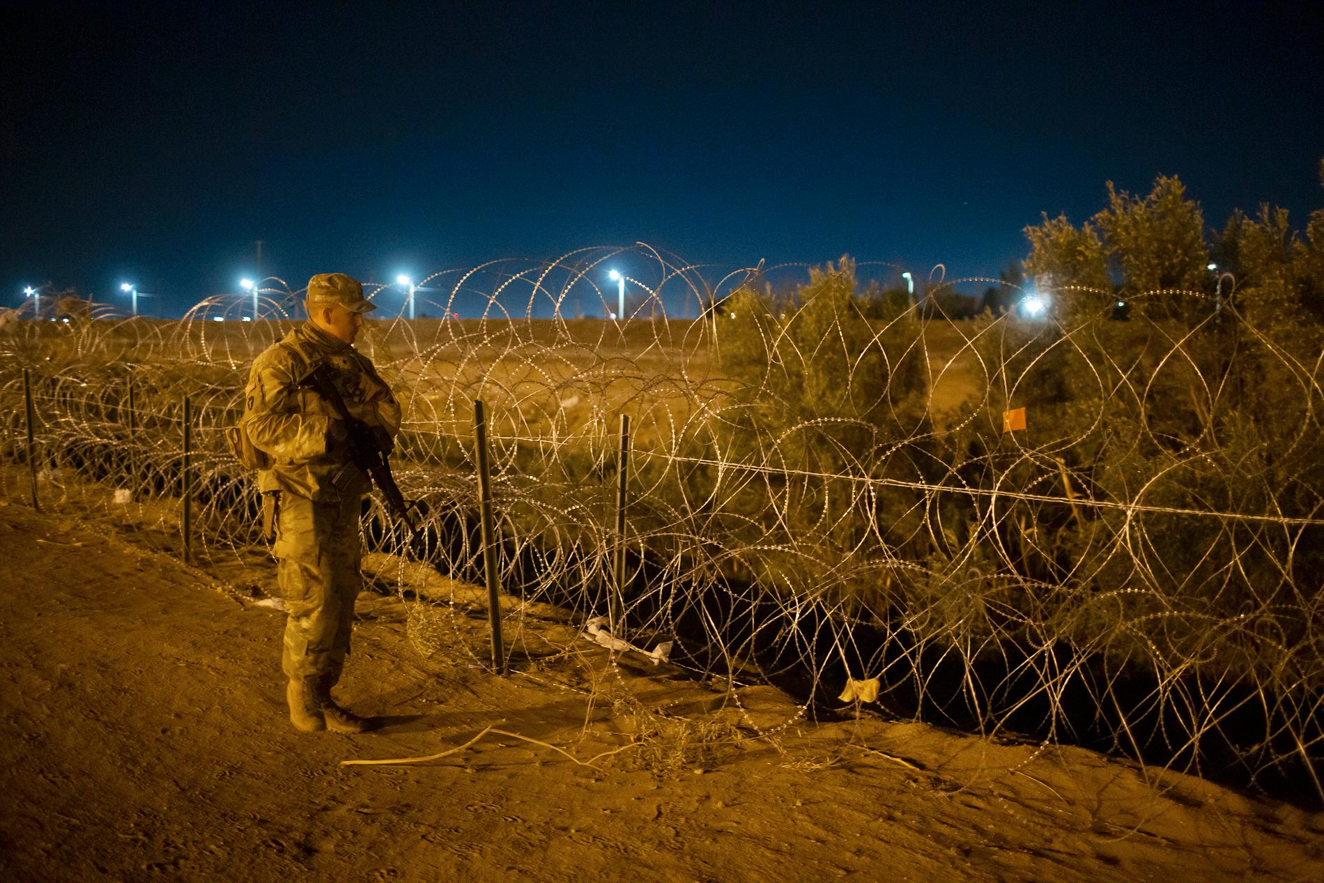 En gränsvakt patrullerar vid ett taggtrådsstängsel nära gränsfloden Rio Grande i Texas.