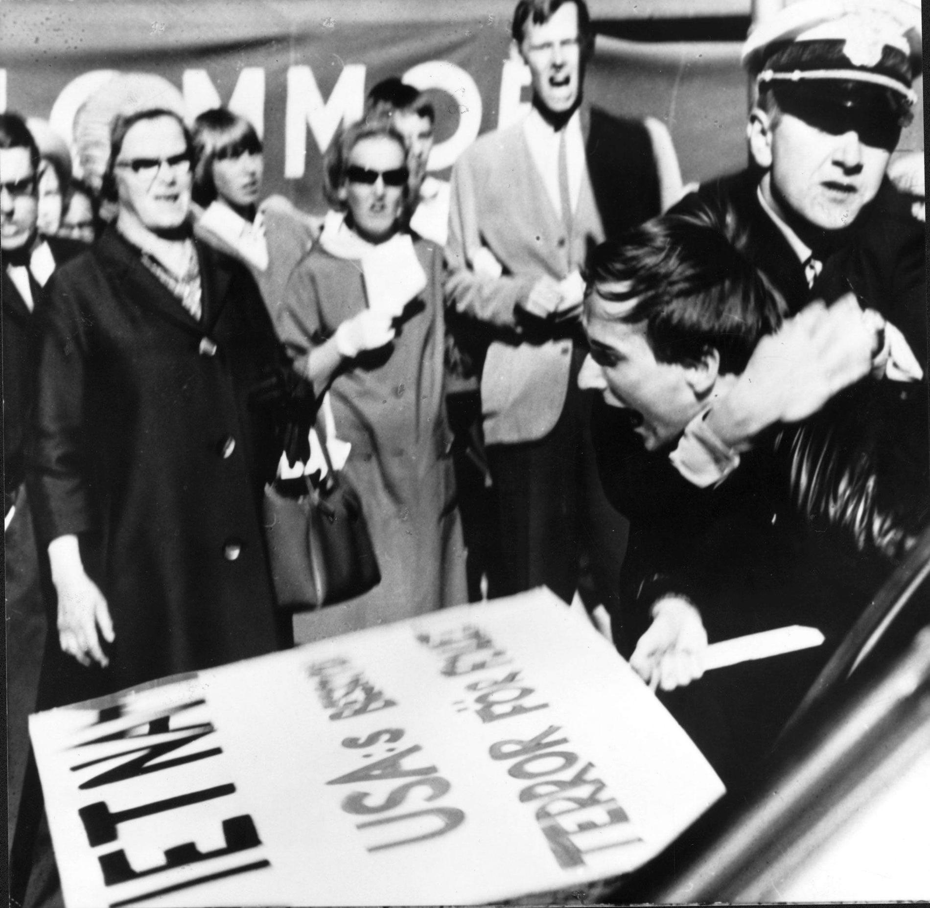 Polisen griper Sköld Peter Matthis under den första svenska  Vietnamdemonstrationen, på Hötorget i Stockholm 1965. 