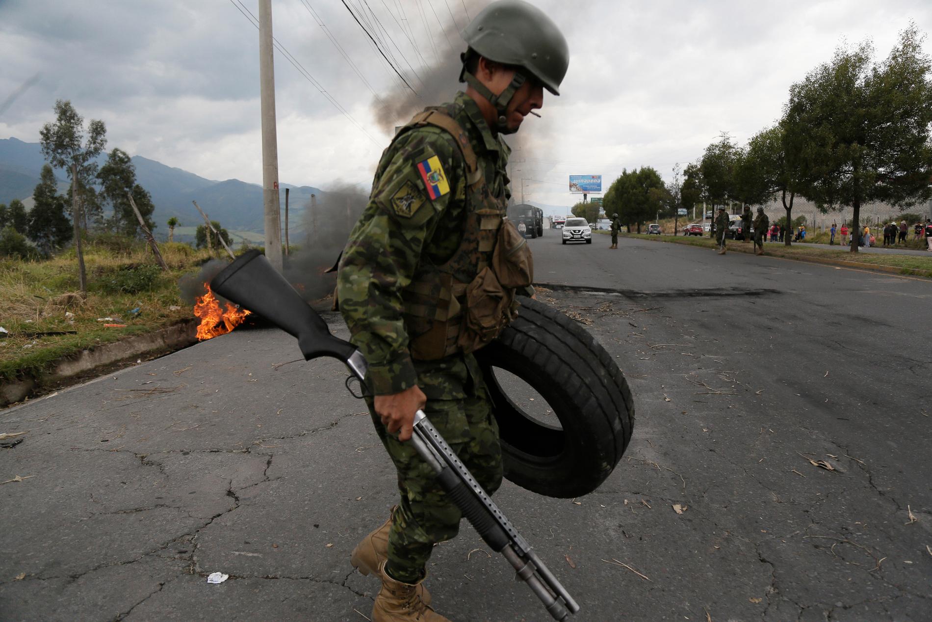 En soldat i Tambillo i Ecuador rensar motorvägen från bråte som lagts dit i samband med protesterna. Bilden är från i lördags.