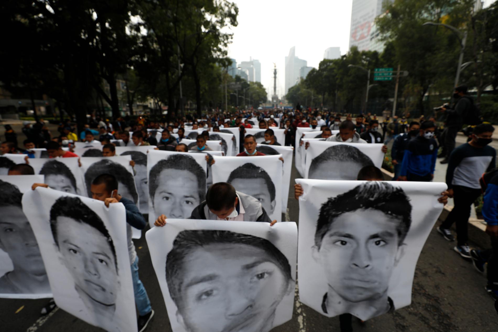 Demonstranter och anhöriga håller upp bilder på de 43 studenter som fördes bort 2014.