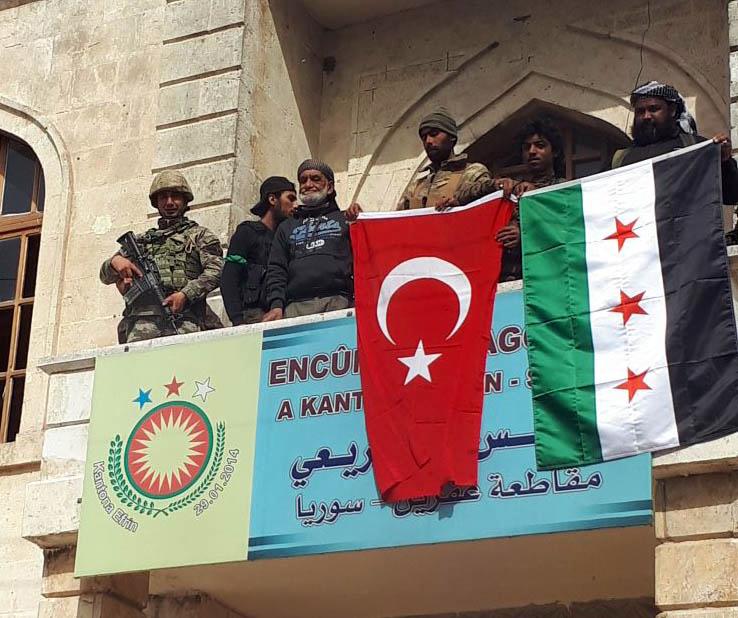 En turkisk flagga bredvid den allierade rebellgruppen Fria syriska arméns flagga i Afrins stadskärna på söndagen.