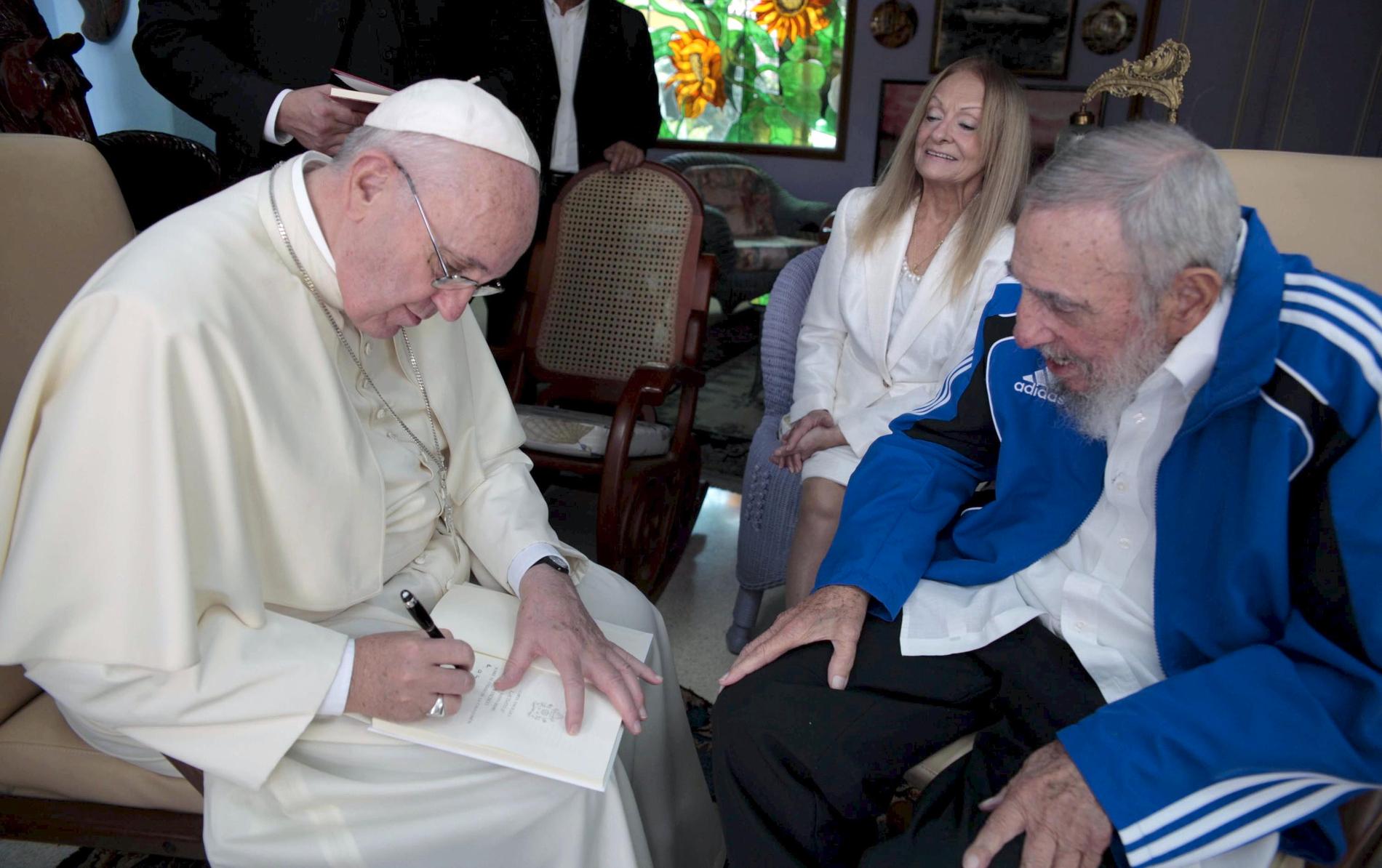 Påve Franciskus skriver i en bok under ett möte med Fidel Castro och hans hustru Dalia Soto del Valle i Havanna, september 2015.