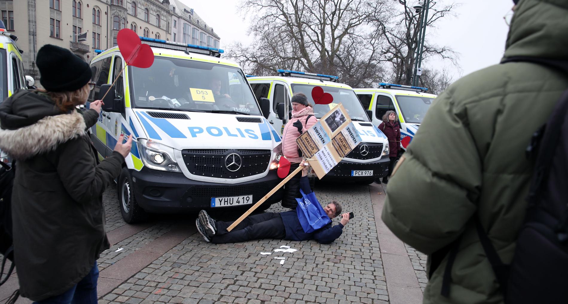 Demonstrant på marken framför polisens buss i Malmö.