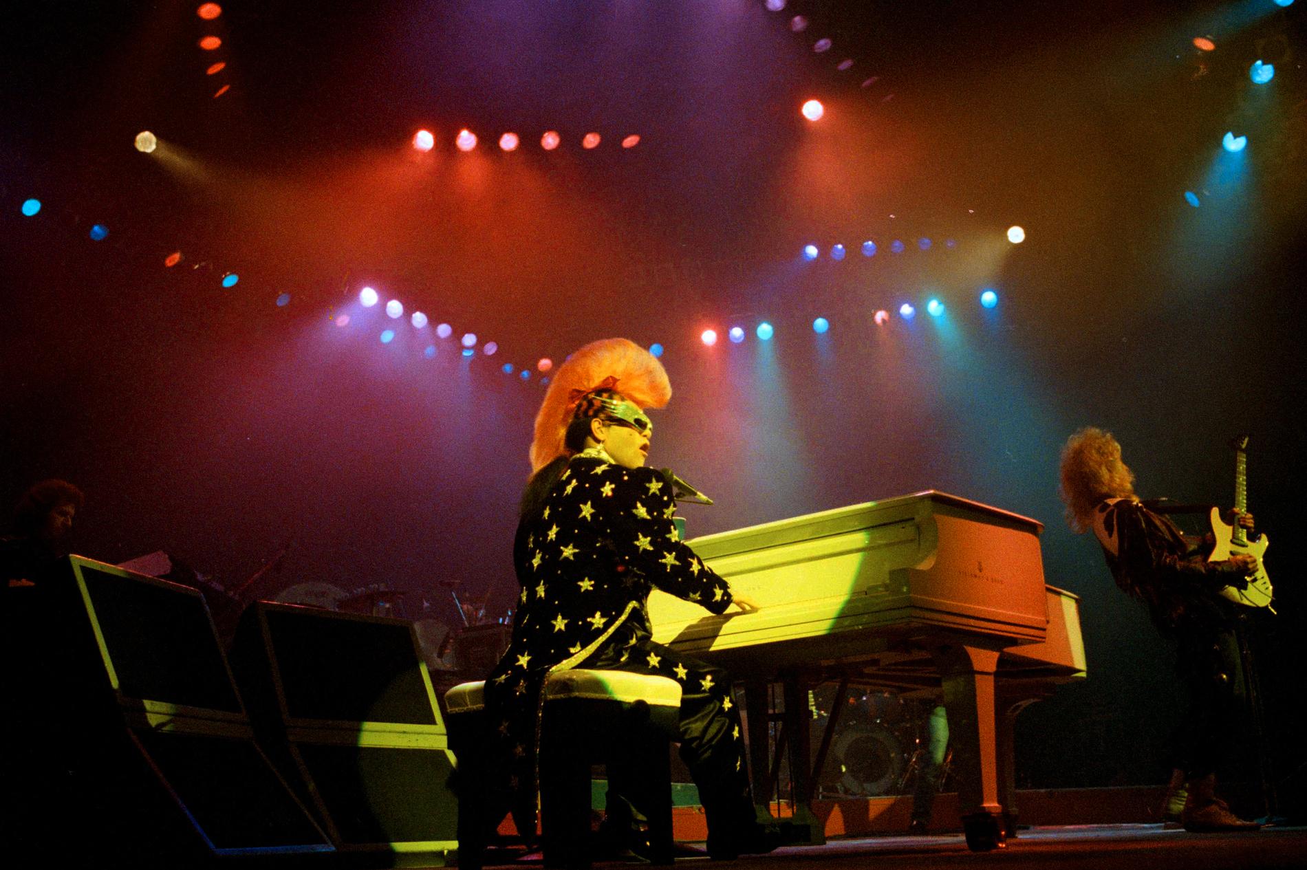 Elton John uppträder iförd en stjärnprydd frack och rosa tuppkam på Universal Amphitheater i Kalifornien 1986. Arkivbild.