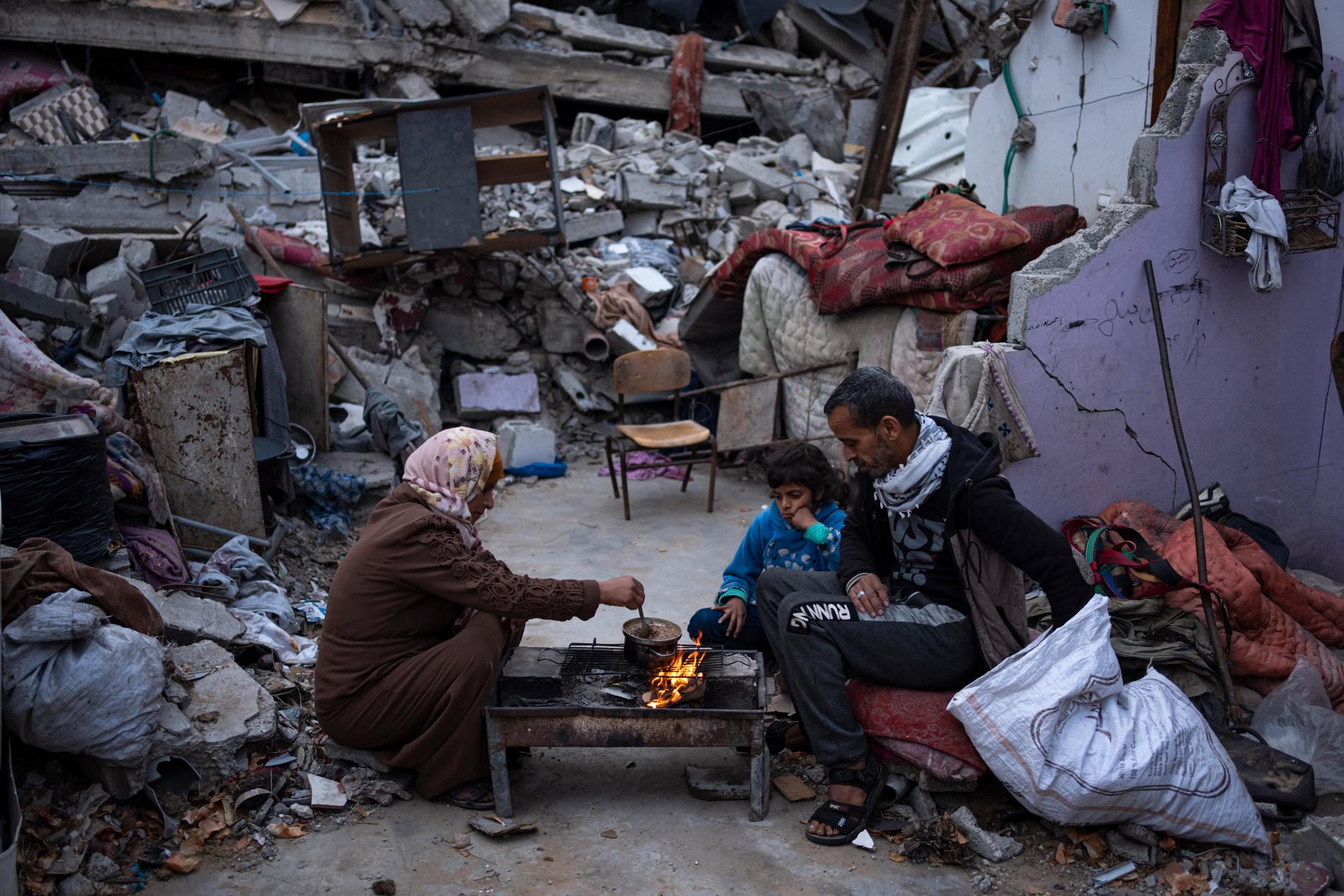 En palestinsk familj äter bredvid sitt sönderbombade hem i Rafah, 18 mars. 