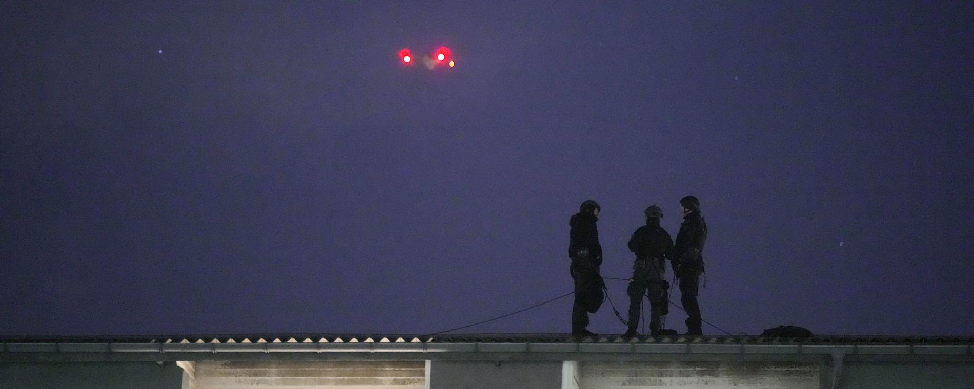 Polis på ett tak i närheten av den lägenhet där gisslandramat pågår. Över syns en av polisens drönare. 