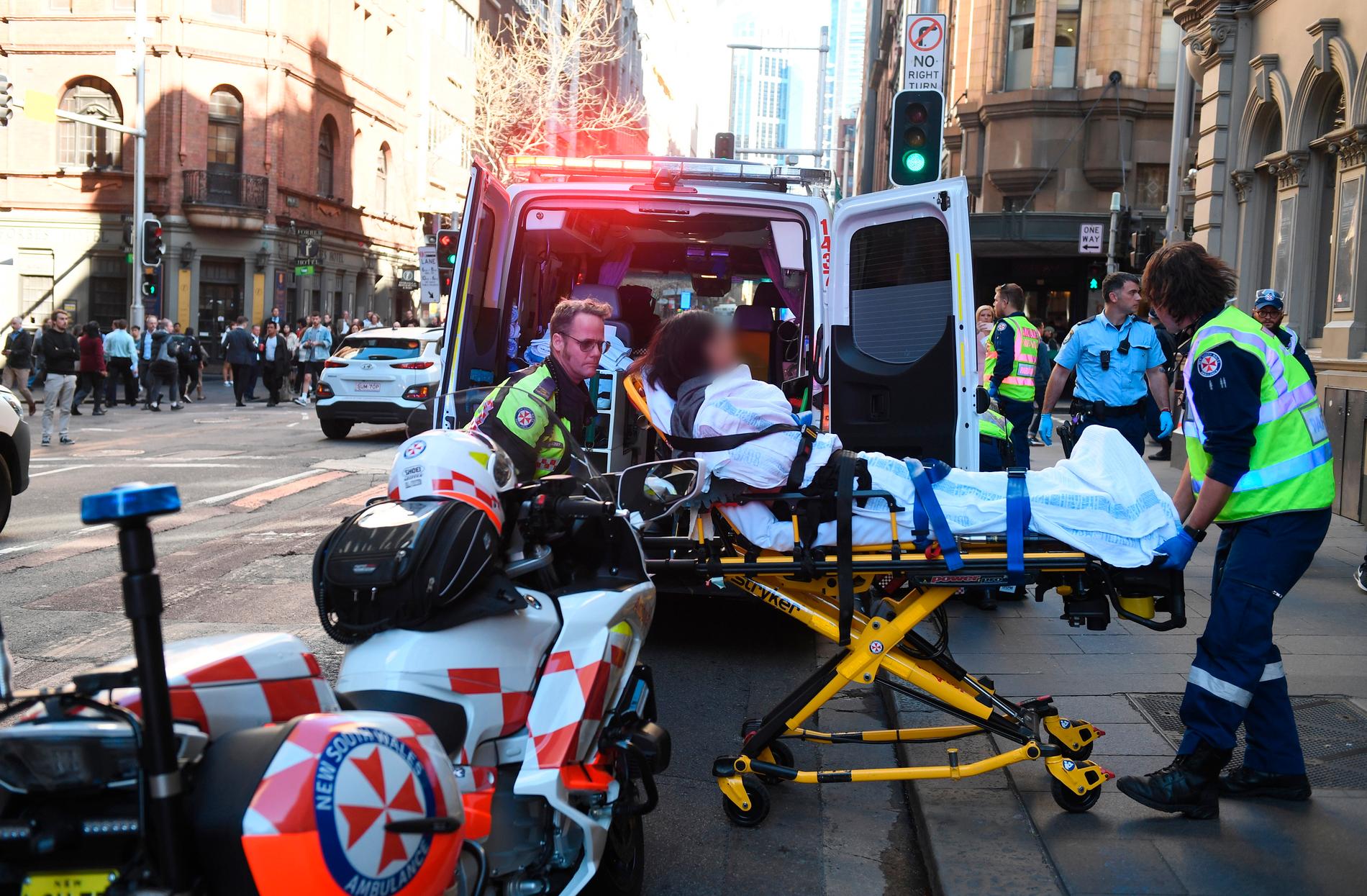 En skadad kvinna tas omhand av ambulanspersonal efter att ha knivhuggits i Sydney.