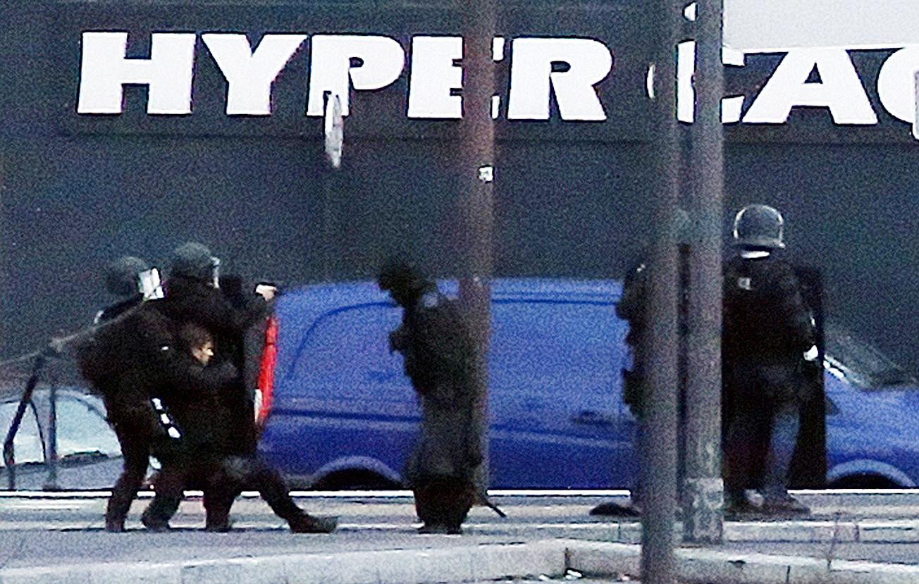 En skadad polis får hjälp av sina kollegor under stormningen av butiken där gisslan hölls i Paris.