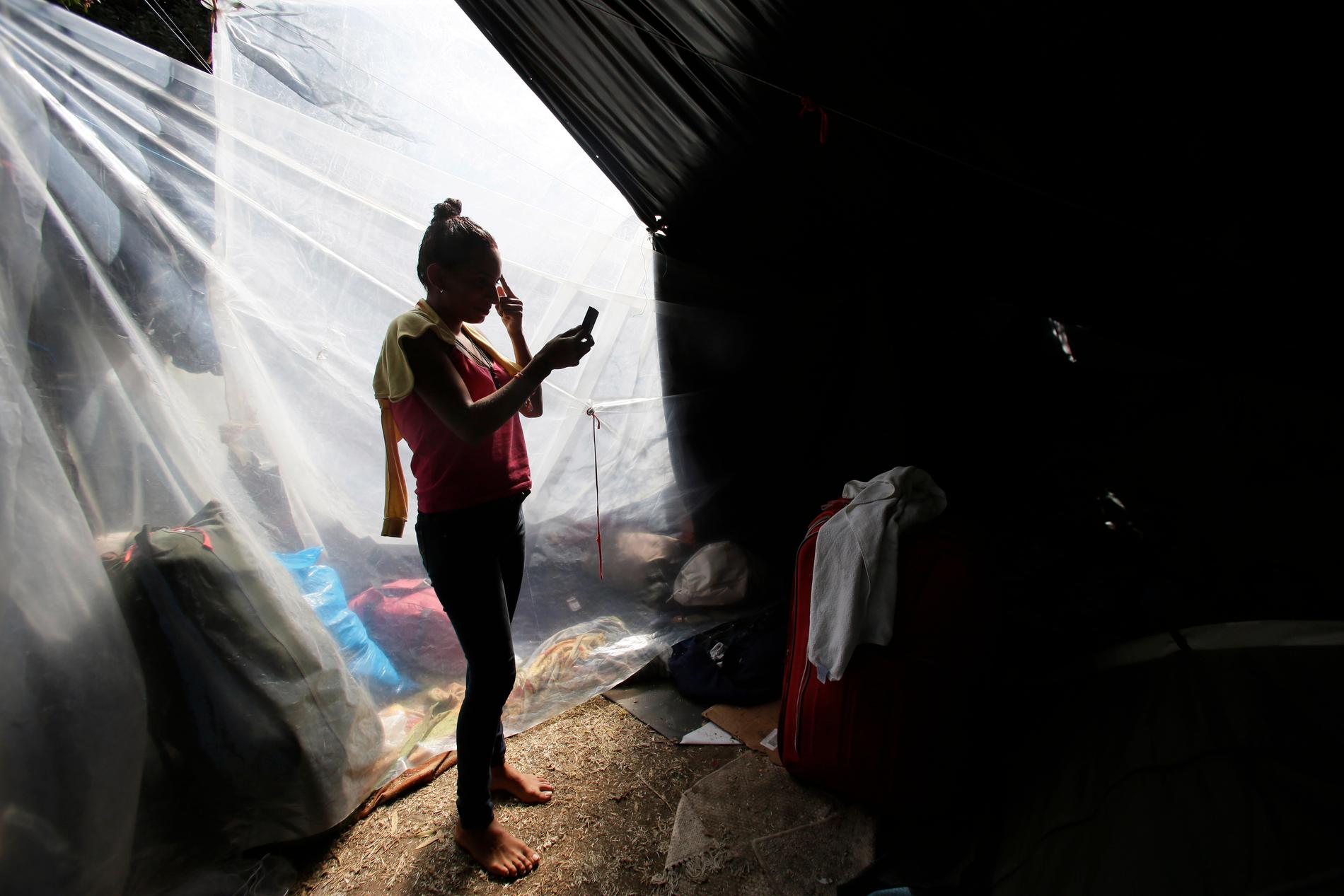 En flykting från Venezuela sminkar sig i ett läger inför arbetsdagen i Ecuadors huvudstad Quito.