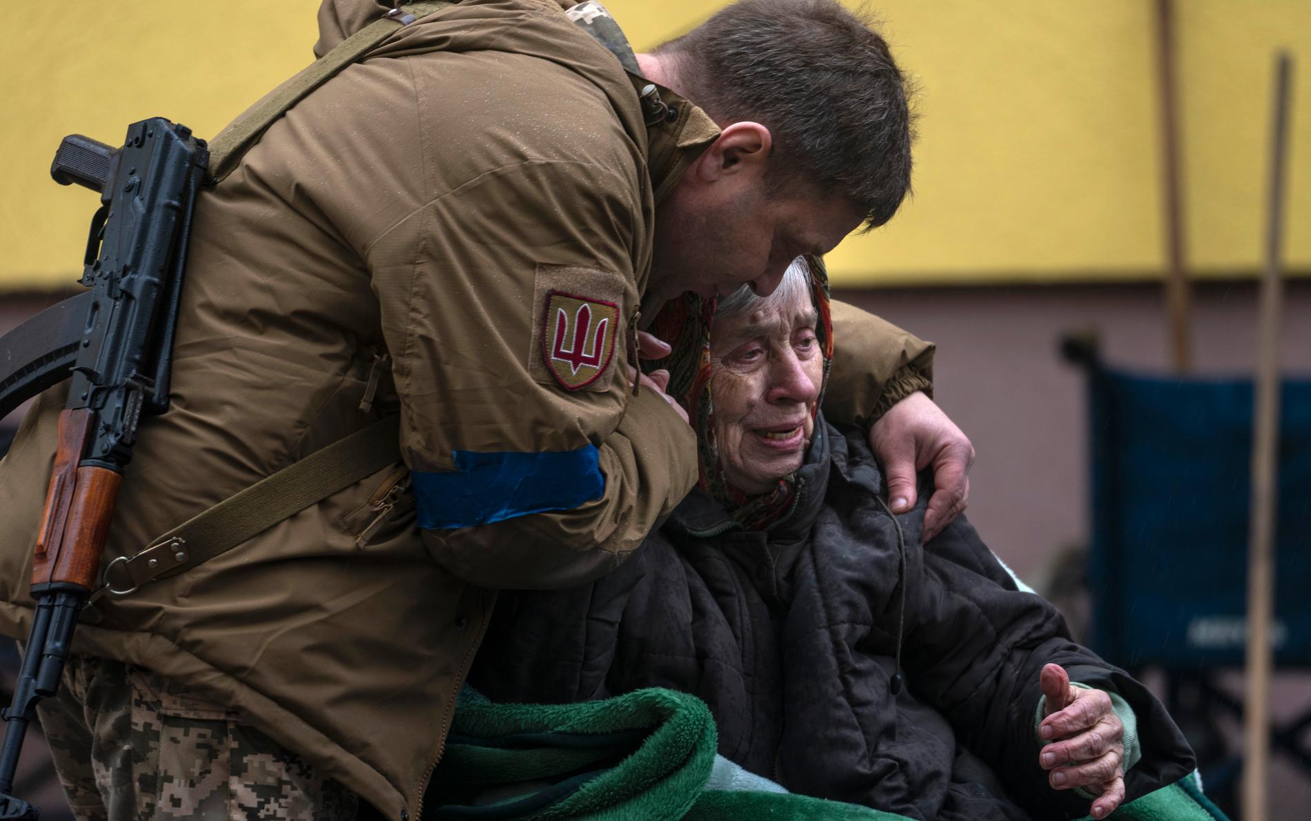 Ukrainsk soldat tröstar 82-årig kvinna som har evakuerats från Irpin.