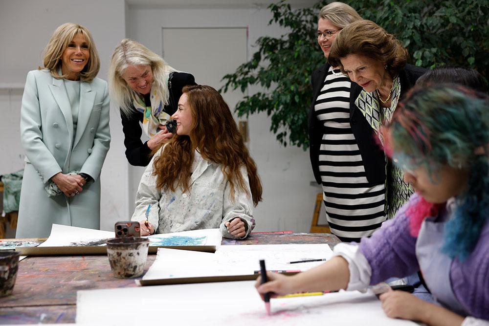 Presidentfrun Brigitte Macron och hennes tolk samtalar med en av de unga konstnärerna från Botkyrka. Drottning Silvia beundrar ett konstverk, till vänster om drottningen står Moderna Museets Gitte Ørskou. 