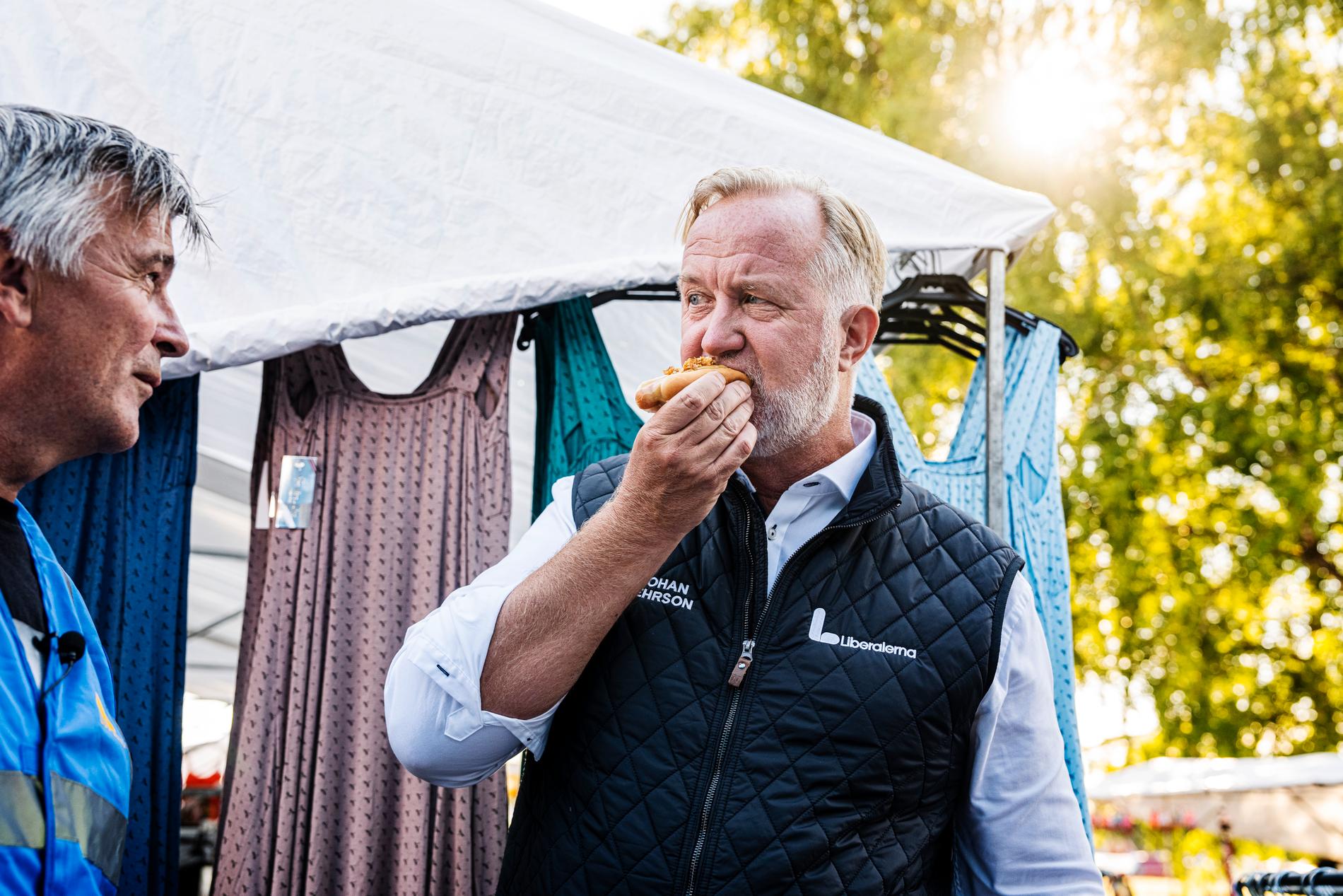 Liberalernas partiledare Johan Pehrson äter en kokt korv på sommarmarknaden Malmmarknaden i Malmköping.