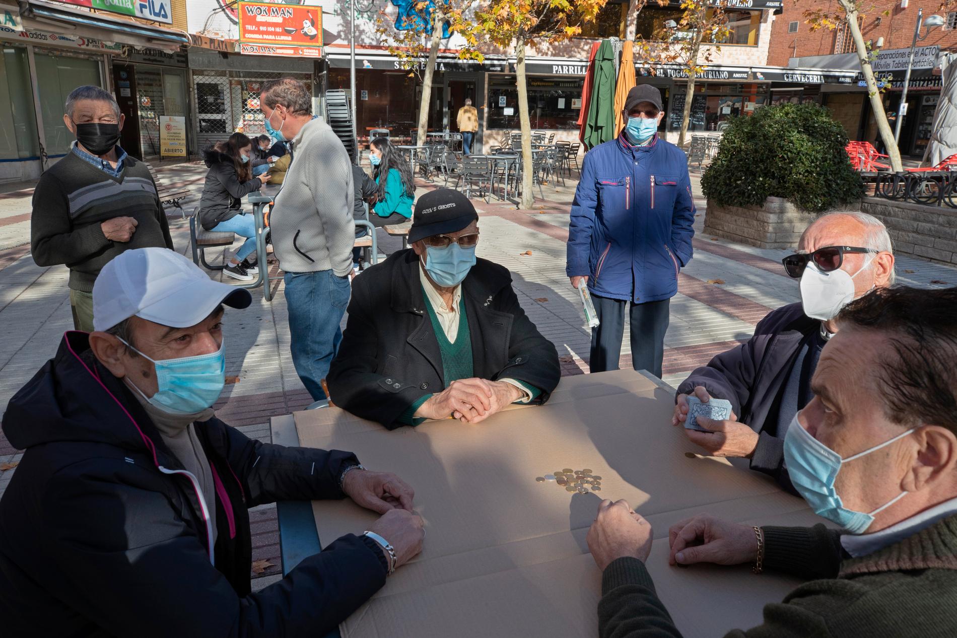 Pensionärer spelar kort på ett torg i den spanska huvudstaden Madrid, som i likhet med den lilla staden Tomelloso drabbats hårt av coronaviruset.