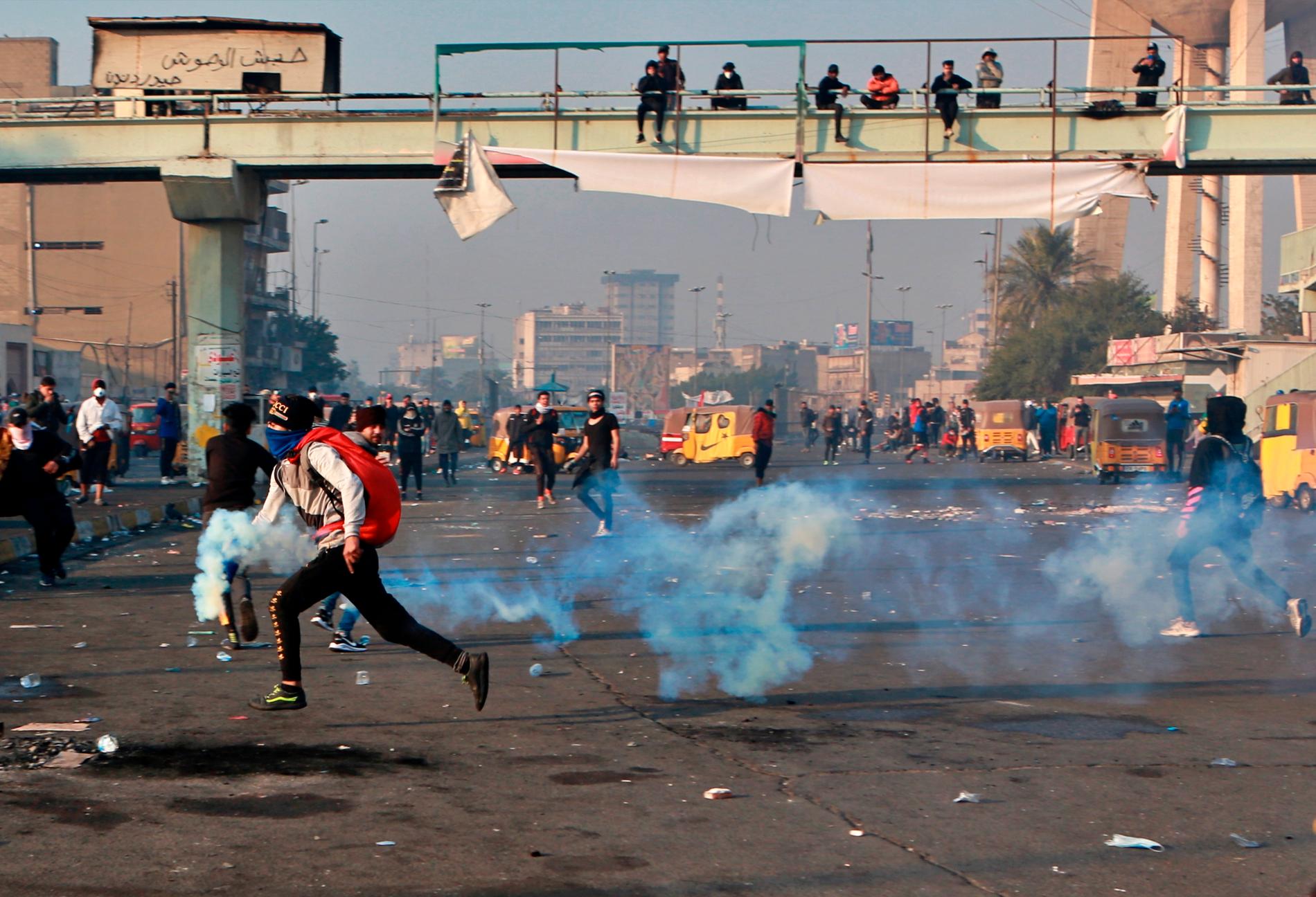 En demonstrant springer med en tårgaskanister i handen i Iraks huvudstad Bagdad på måndagen.