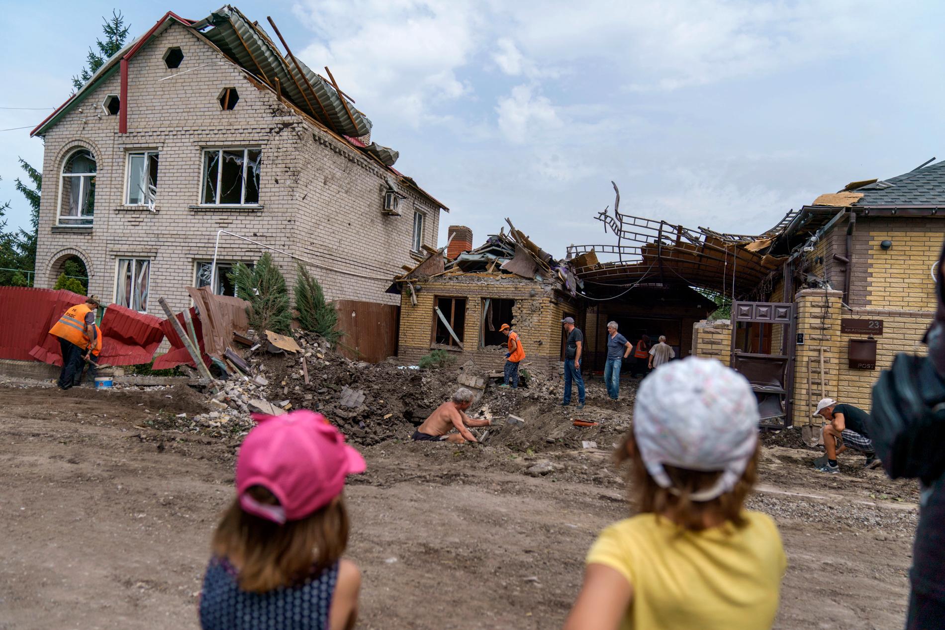 Barn ser på när räddningsmanskap går igenom skadorna efter en granatattack i Kramatorsk i östra Ukraina. Inga personer skadades i attacken i fredags.