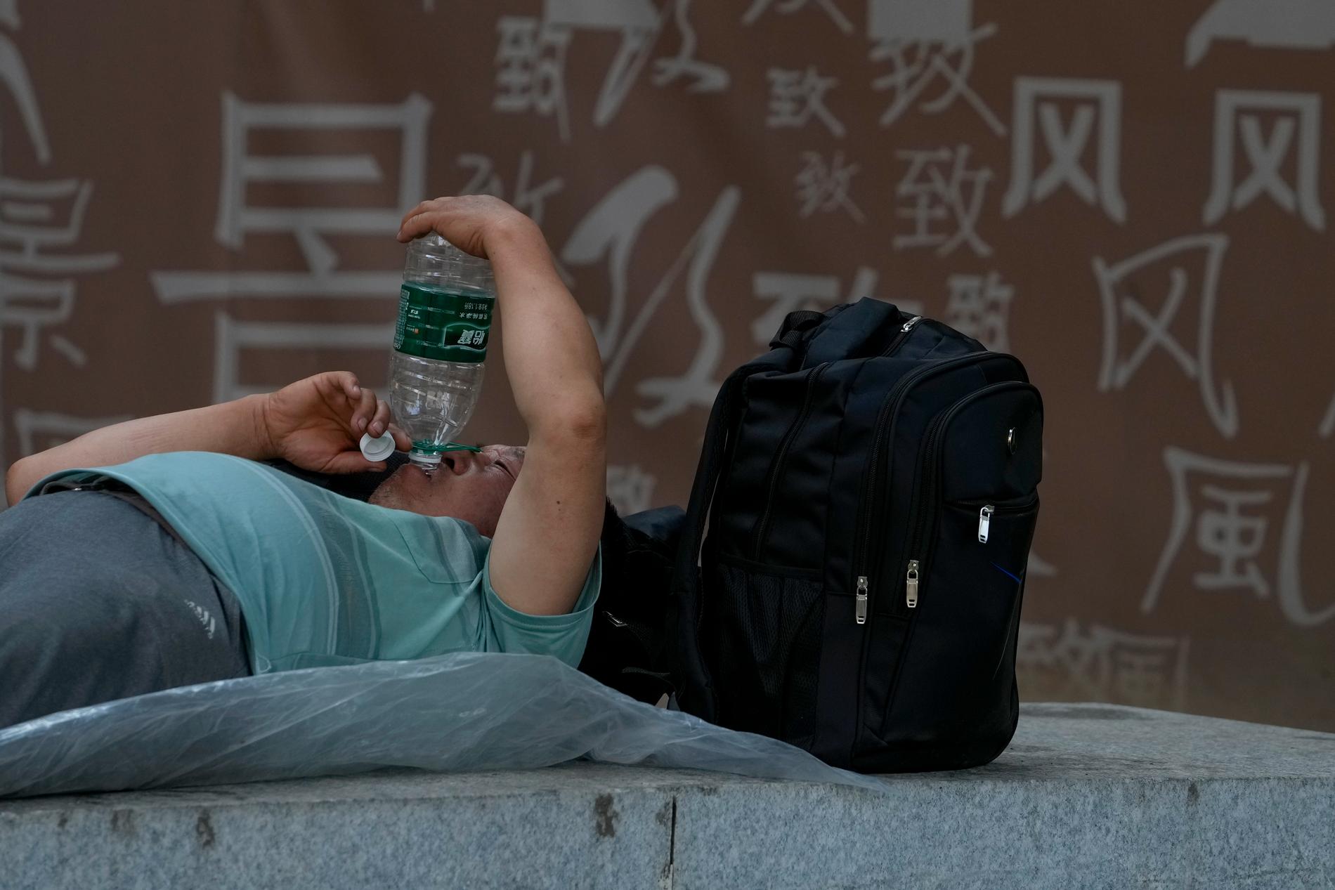 En kvinna tar skydd i skuggan i Peking. 